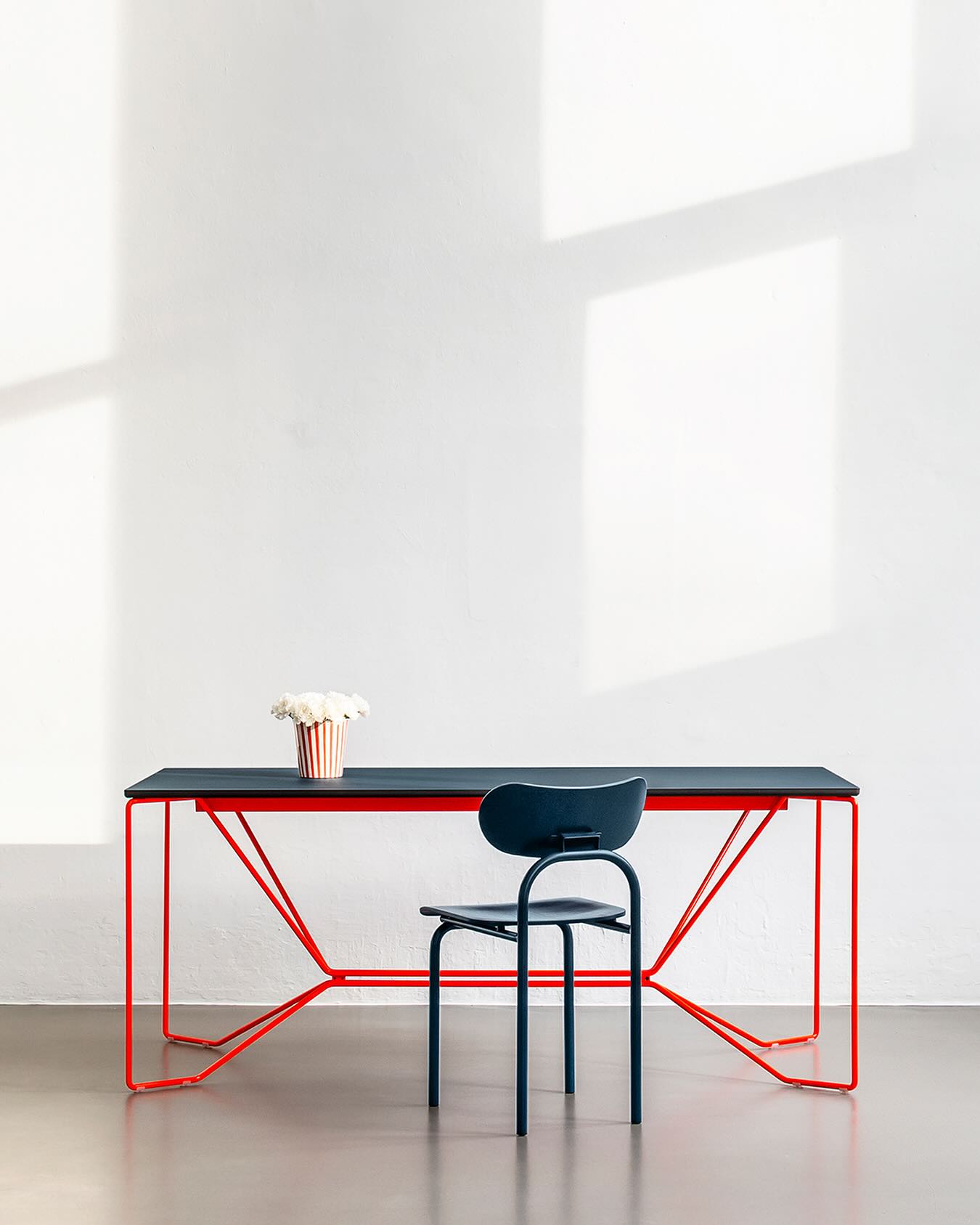 SAME SAME TABLE
Solid as a rock. Dining table and desk. The delicate steel frame is bent by hand. It consists of two identical parts that reflect each other and are only fastened at two points. The tabletop is crafted from dyed-through MDF with a linoleum surface.