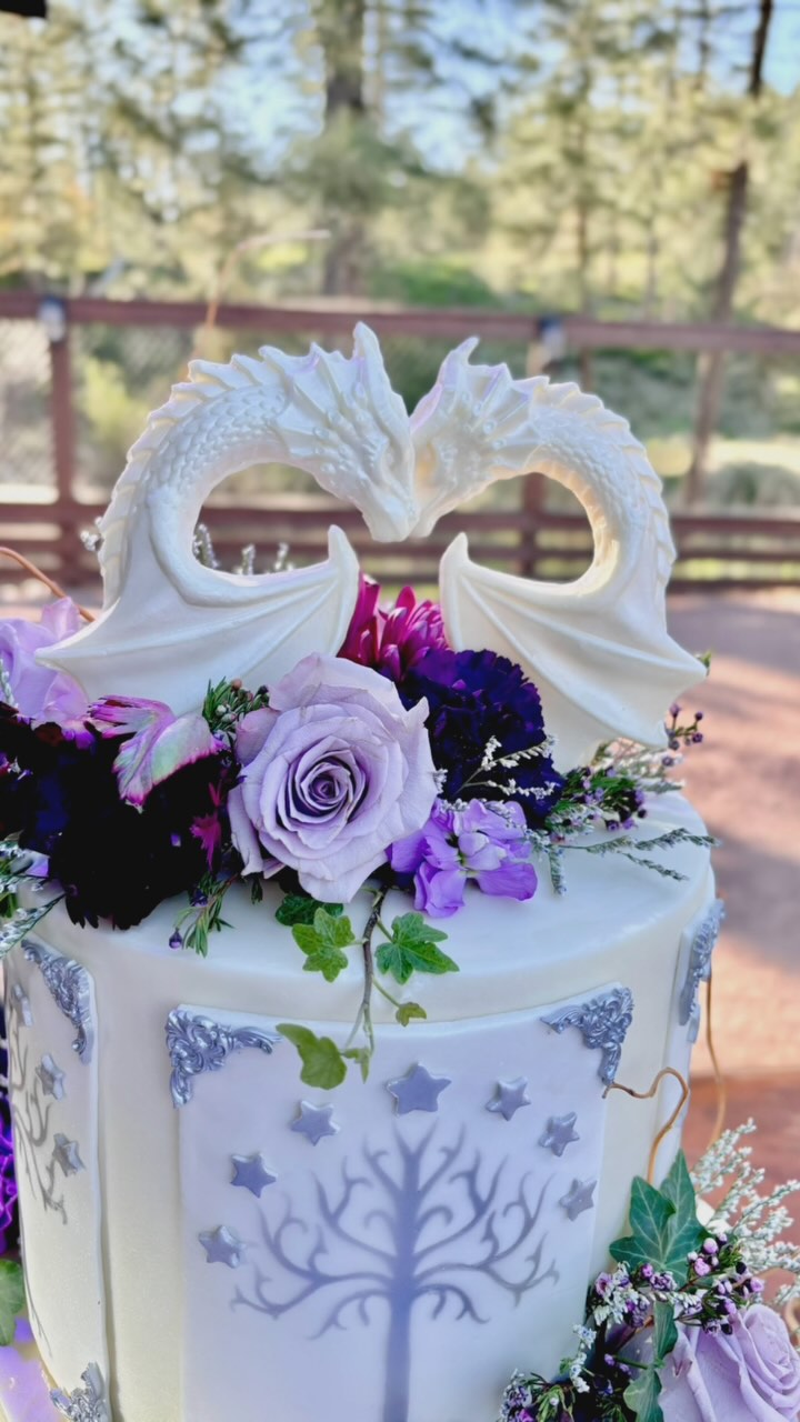 Congratulations to these Lord of the Rings fans!! 🧙🧙♀️💍🍃 Emily & Paul tied the knot at the stunning @cabinsonstrawberryhill
We love #lotr and the design these two decided on! This centerpiece features several elements of middle earth 📜 including the Tree of Gondor, a pair of white love dragons, silver filigree, LOTR symbols, white birch trees, beautiful fresh florals, ivy & twigs and at Emily’s request, we can’t forget the little hints of edible “moss” (420 inspired) 😄
All design pieces (aside from the florals and twigs) are completely edible! We hope you loved your wedding statement centerpiece for your big day as much as we loved creating it!
We wish you both a very happy journey together 💜💜💜 Thank you again for trusting us with your love story!
#lotrwedding #lordoftheringsart #edibleart #lotrcake #lovedragons #dragonlovers #paysonazbakery #kendrascountrybakery #mountainwedding #phoenixfoodie