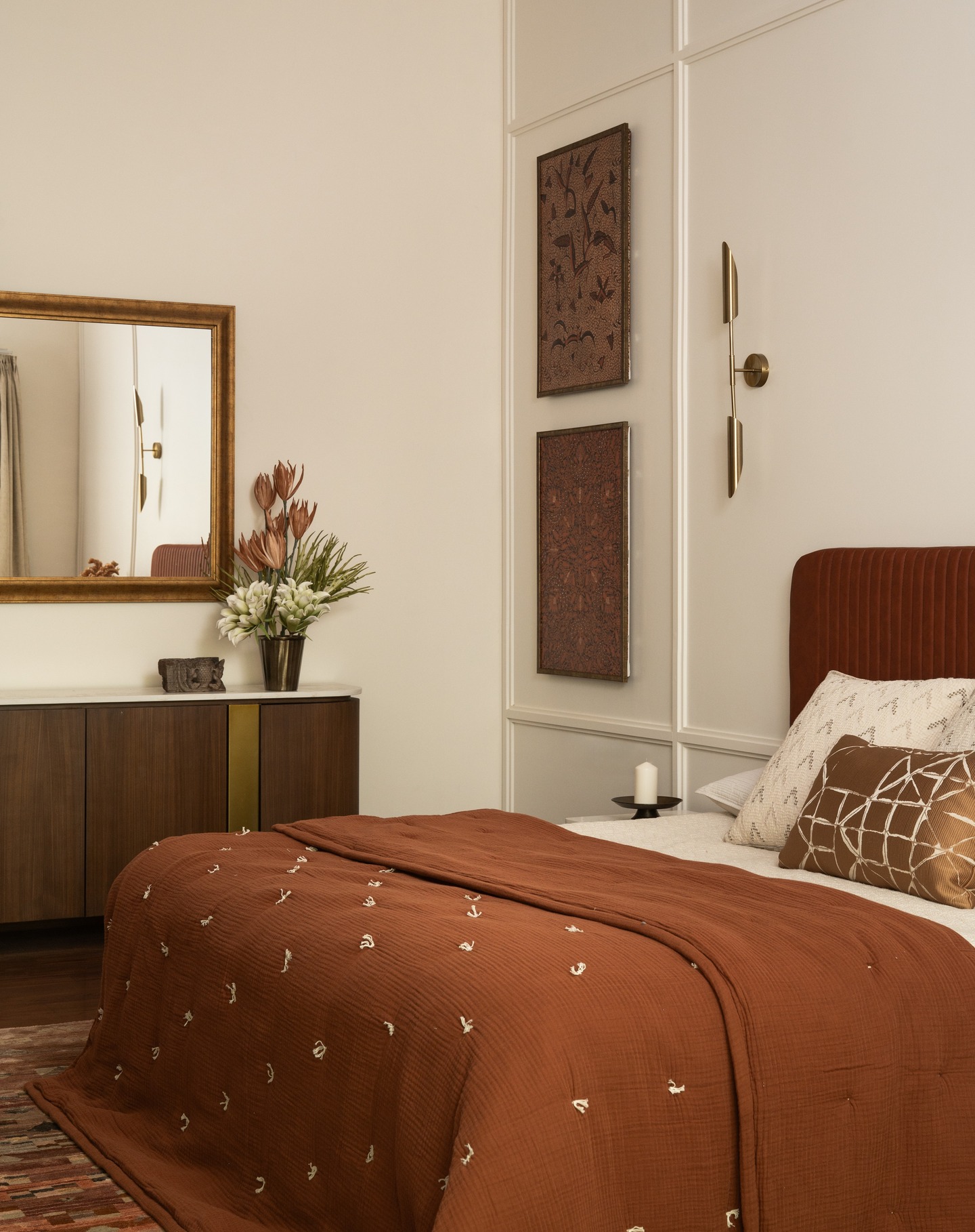 Project Thuzha ~ The Master Bedroom!
This warm, elegant bedroom blends earthy tones with refined textures for a serene, sophisticated retreat. A rust-colored, ribbed headboard anchors the space, complemented by a hand-embroidered quilt and patterned cushions. The ivory paneled wall adds depth, while vertical art and brass sconces introduce a modern, curated edge. A dark wood credenza with brass accents and a floral arrangement enhance the organic, luxe aesthetic. Thoughtful and tranquil, the design balances comfort with quiet luxury.
Design and execution : Furbishy
Photography : Nayan Soni @nayansoni21
Cinematography: Create Stories @createstories.in
Styling : Shivani Raina @theshalomhome
