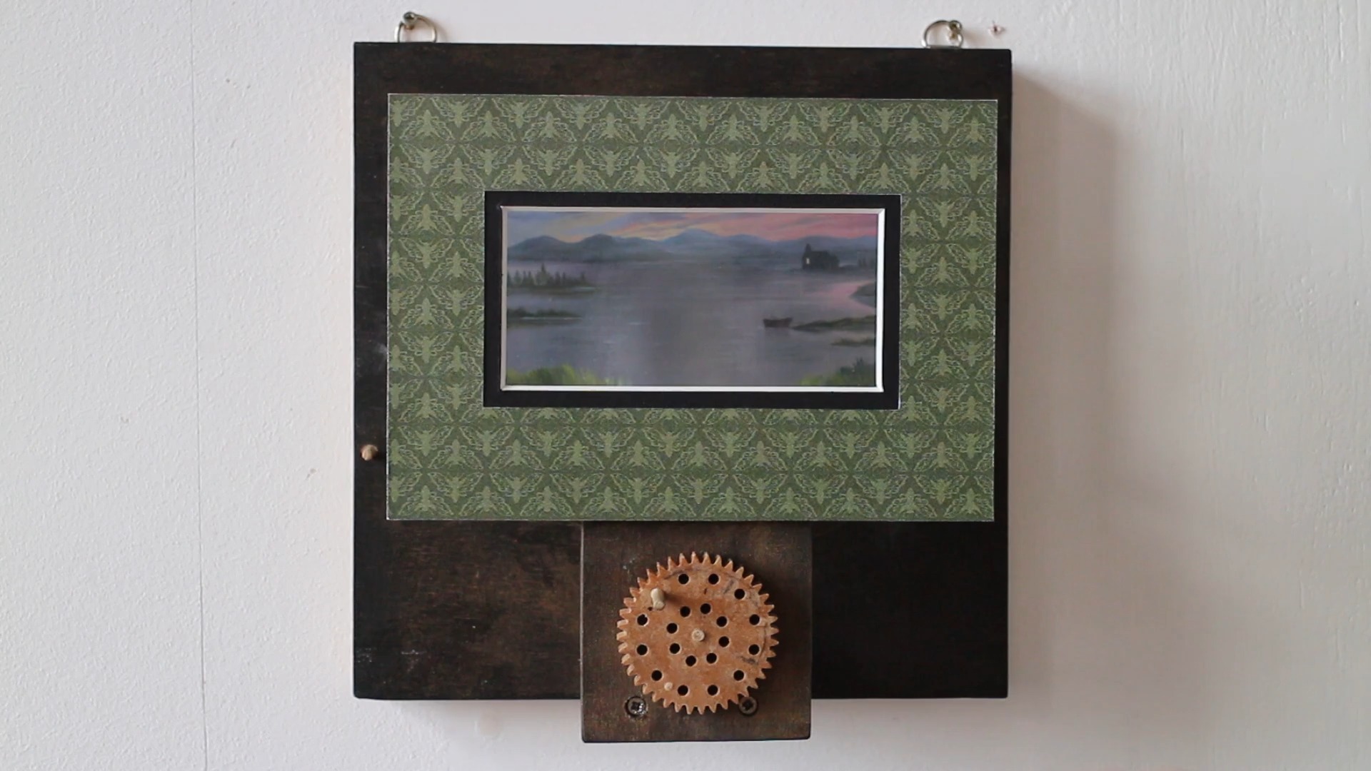 The Rusty Lake Pepper’s Ghost Illusion.
This automaton features a small, hand-painted landscape depicting the lake from the game Rusty Lake.
Using a Pepper’s Ghost illusion, two ghostly figures—The Corrupted Soul and Laura—appear above the scene, adding an eerie element.
The Pepper’s Ghost illusion works by reflecting light off a transparent surface, such as glass or plastic, placed at a specific angle between the viewer and the scene. In this setup, the ghostly images are projected from a hidden space onto the reflective surface, creating the illusion that they are floating in front of the landscape. This technique is often used in theater and haunted houses to produce realistic spectral effects.
In person, the illusion creates a striking 3D effect, making the figures appear as if they are truly hovering in front of the background.
The Pepper’s Ghost technique typically relies on lighting the ghostly figures, but in this case, a dark apparition—The Corrupted Soul—can also be seen. This raises the question of how this figure appears without being illuminated. But the lake does not reveal all its secrets!