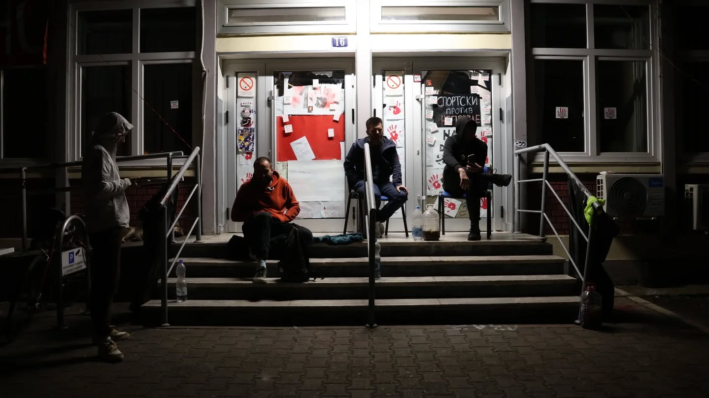 Na straži kod DIF-a - Zborovi Novog Sada su pozvali da se ljudi prijavljuju u smene ispred DIF-a posle onog pokušaja razbijanja bloakde. Prošli put isred RTV-a rasterali su nas u 5 pa sam rešio da dođem od 4 do pola sedam.
Kad sam došao zatekao sam oko 15-20 ljudi, neke od kojih sam dobro poznavao. Sedeli su na stepnicama, ili na stolicama u manjim krugovima, ogrnuti ćebadima. Bilo je i starijih i mlađih, neki su spavali na ćebadima razvučenim na travnjaku čak. Bila je i jedna veselija grupa beogradskih DIF-ovaca iz Beograda koji su došli da podrže kolege. Bilo je mirno, periodično na svakih sat i po dva, malim parkingom do fakulteta, prošla bi škoda sa dvojicom putnika. "Bezbednjaci, policija ili BIA", rekli su mi. Pomislio sam: "Merkaju koliko nas ima", a onda se vrlo zabrninuo jer ovako mali broj nas bi samo bio u stanju da popije batine. Ipak ne bi tako lako ušli na fakultet DIF-ovci su od ulaza napravili srednjovekovna utvrđenja. Imali su bar šta da nabacaju na njih, sve od kozlića do strunjača.
Vreme je prolazilo lagano u druženju. Oko pola šest predružila nam se jedna žena srednjih godina. Ljubazno pozdravila ljude koji su stojali malo dalje donela neku čast, sok i neku hranu. Bila je vrlo dobronamerna i zabrinuta, govorila je kako je sve ovo sramota. U jednom momentu rekla je: "Ali da znate ovi policajci što su tukli ljude to nisu naši policajci, ne to su Dodikovi policajci, oni su dovedeni da biju." Jedna pristuna studentkinja, bliže meni, besno je počela do govori sebi u bradu:
"Od ovoga mi je muka. Šta pričaš ti ženo! Pa koliko danas su vas tukli ovde, ti bi da ih braniš. Poludeću od ovoga!"
Ja i još jedan drugar smo se složili, ali smo smirivali situaciju. Nismo hteli da je žena čuje, iako je bila u pravu. Rekli smo da ni mi ne verujemo policiji i da nam je cela ona slika danas sa ljudima koji ih tapšu po ramenu, posle batinjanja,besmislena. Studentkinja nastavila da negoduje:
"Ljudi pričaju te gluposti sebi, jer im je lakše da misle da ih ne tuku njihove komšije. "
Uskro je počelo da svanjiva, DIF je, bar za sad, bezbedan.
#studentprotests
#studentskiprotest
@studenti_u_blokadi