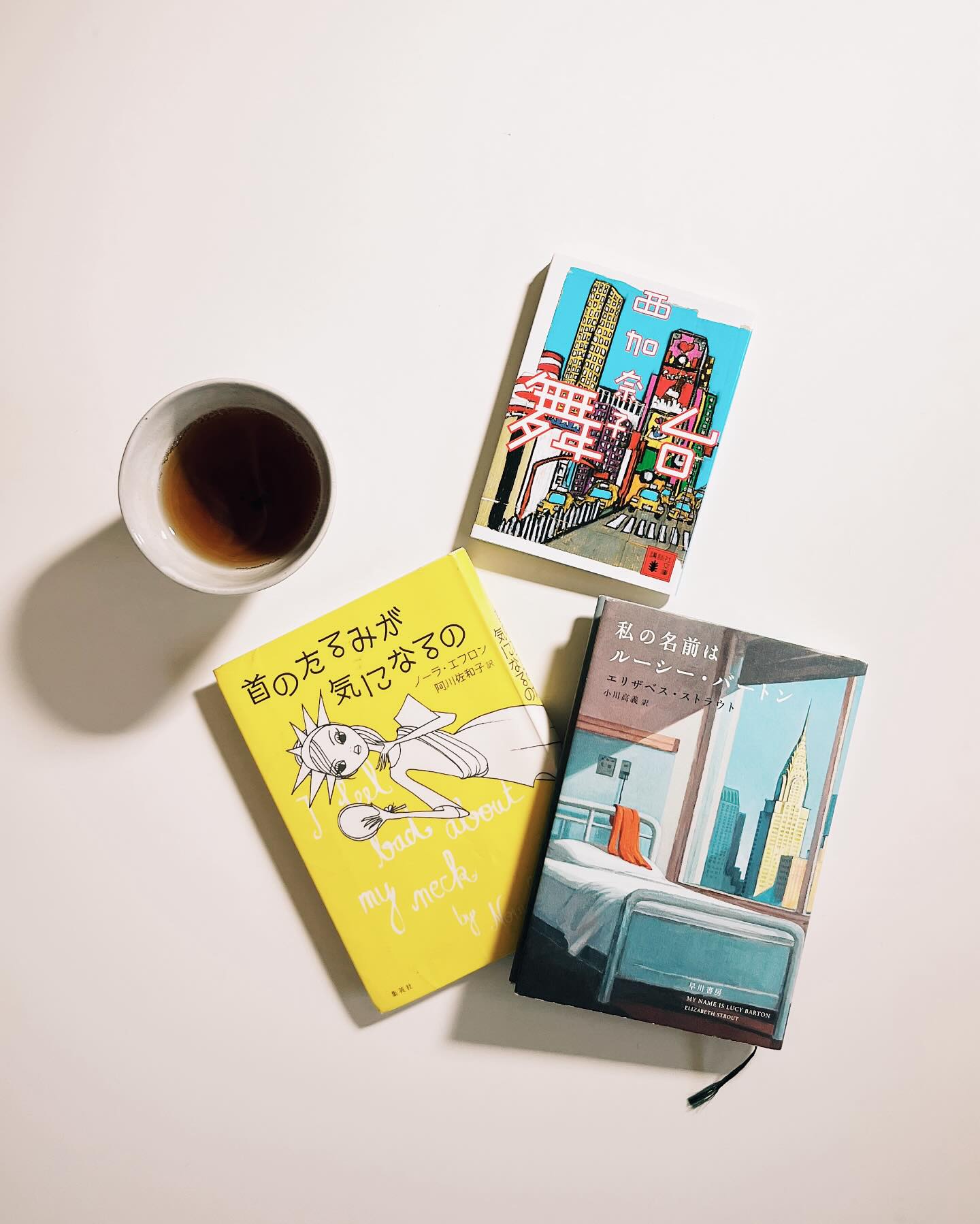 「ニューヨーク」というテーマで3冊。今回は小説2冊に、エッセイ1冊です。
- -
Just another Golden Week holiday post recommending books to Japanese readers - two of which can be read in English, as that is the language in which they were originally written.
I didn’t set out to read three books that were set in NY, but did want to be reread Kanako Nishi, one of my favorite Japanese authors, whose novel “BUTAI (The Stage)” is set in the city. (It’s not translated out of Japanese. But keep your eyes peeled for translated work from this author next year!)
Pictured also are the JP versions of Elizabeth Strout’s My Name is Lucy Barton and Nora Ephron’s I Feel Bad About My Neck. Both books I’m delighted are available for Japanese readers.
Will be back to posting about English reads soon. xo
- -
久しぶりに再読したい小説があって、それを本棚から取り出して読んでいると、そういえばあれも読みたい、そうだあれもと連想し、気づくと「ニューヨーク」がテーマの本を3冊手にしていた。
きっかけとなったのは西加奈子さんの『舞台』(2014)。読むのは10年ぶりぐらいだろうか、NYが舞台の小説です。
📘「NYが舞台」と聞くと素敵だが、初めての海外、『地球の歩き方』を丸暗記し挑んだ29歳の葉太はNY初日に鞄を盗まれ、パスポートもお財布も全て失ってしまう。一日現金4ドルで帰国までどう生き延びるのか。初めて読んだ時、必死であるはずなのにダサく見えることに怯え、「余裕です」と周りに見せることに命をかける葉太の自意識過剰っぷりに、「私じゃん!」と震え、どこまでもややこしいこじらせっぷりを言葉にしてくれた西さんに感嘆した。自分が今の歳になり、彼の「格闘」が若いからだけではないことを再確認し、救いとlow-keyな絶望にまた叫びそうになった。
📕 『舞台』で葉太は自分を「獲得」していこうとするのだが、ポイントとなるのが彼の両親の存在、特に田舎から都会に出てきて作家として成功した父親と、その父親に合わせてばかりいた母への嫌悪感。同じく「両親」「田舎」「NY」がキーワードとなっているのが、アメリカのピューリッツァー賞作家エリザベス・ストラウトのベストセラー小説『私の名前はルーシー・バートン』(2016)。日本語訳は小川高義さん。NYで作家として食べていけるようになったルーシーが、何年も前に入院した際、疎遠だった母親が田舎から出てきて共に病室で過ごした5日間を描く、派手さを必要とせず淡々とした、でも後半へ続くにつれ一気に読んでしまう小説。ルーシーが語る、ルーシーの人生について。(読みながらタラ・ウェストウーバーの『エデュケーション』という壮絶なノンフィクションを思い出した)
📙日本からNYへ辿り着いた青年と、アメリカの田舎からNYへ出てきた女性。共にどうすることもできない過去(と両親の過去)を背負い、自分を変えていこうとする。(ルーシーは変えようとしてきた)そんな二人にNYは平等に冷たく、あたたかい。そんなNYを実際に「あたたかく面白い街」にしていたひとり、NYを舞台に何本もスマッシュヒット映画を撮り、エッセイストとしても暗い世界や「老い」などのテーマを笑いに変えてしまうノーラ・エフロン。エッセイ集『首のたるみが気になるの』(2013) 、元のタイトルが「I Feel Bad About My Neck」(2006) なので日本語訳を見て吹き出した。訳者は阿川佐和子さんで、訳がまた素晴らしく面白いのです。
- -
ニューヨーカーは誰もが好き勝手しているようで、自信もありそうで…自意識過剰な人間をさらにそうしてしまう、中毒性のある街。冷たくて、あたたかい。私もたくさん恥をかいたなーあの街で、と思いながら。いや、だから。誰も見てなかったって。自意識、エゴ、どうにかしてと、この本三冊を読みながら久しぶりに思いました。