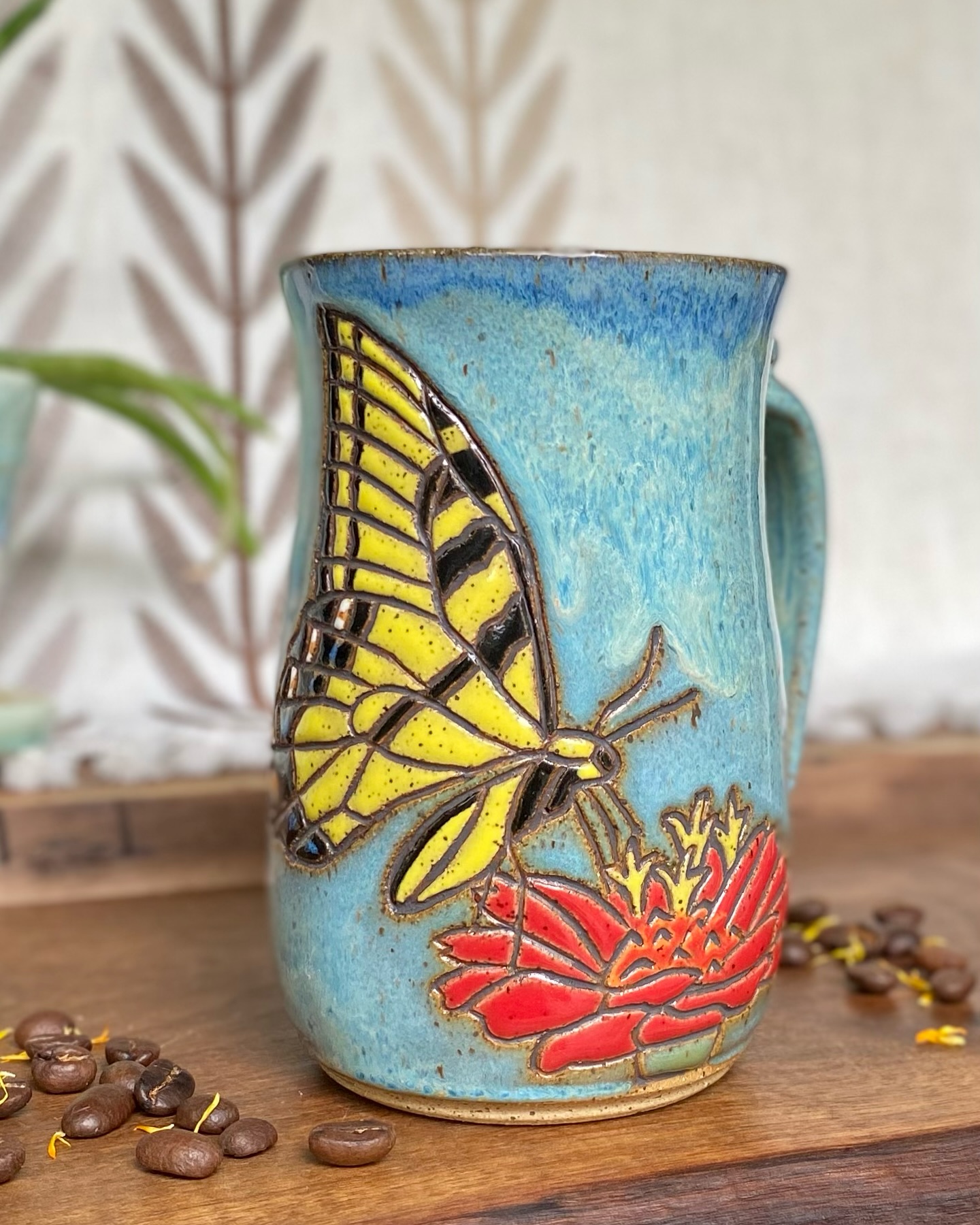 Today while I was resting, I saw a yellow swallowtail flitting around and enjoying the blooms on a rhododendron just outside the window.
It was so beautiful and uplifting I started reading about the symbolism. Swallowtails are often seen as signs of transformation and hope, and rhododendrons represent resilience, which makes sense to me. I’ve seen some amazing rhododendrons on hikes that look like they’ve lived as long as the rocky ledges they cling to.
And while it’s no surprise that a butterfly symbolizes transformation, it’s a good reminder that even when we can’t see change happening, it’s still unfolding. Just like healing, slow, quiet, and steady. Even when it feels invisible, it’s there.
This photo is of a mug I made last summer featuring a yellow swallowtail on zinnia, I look forward to carving one on rhododendron this summer.