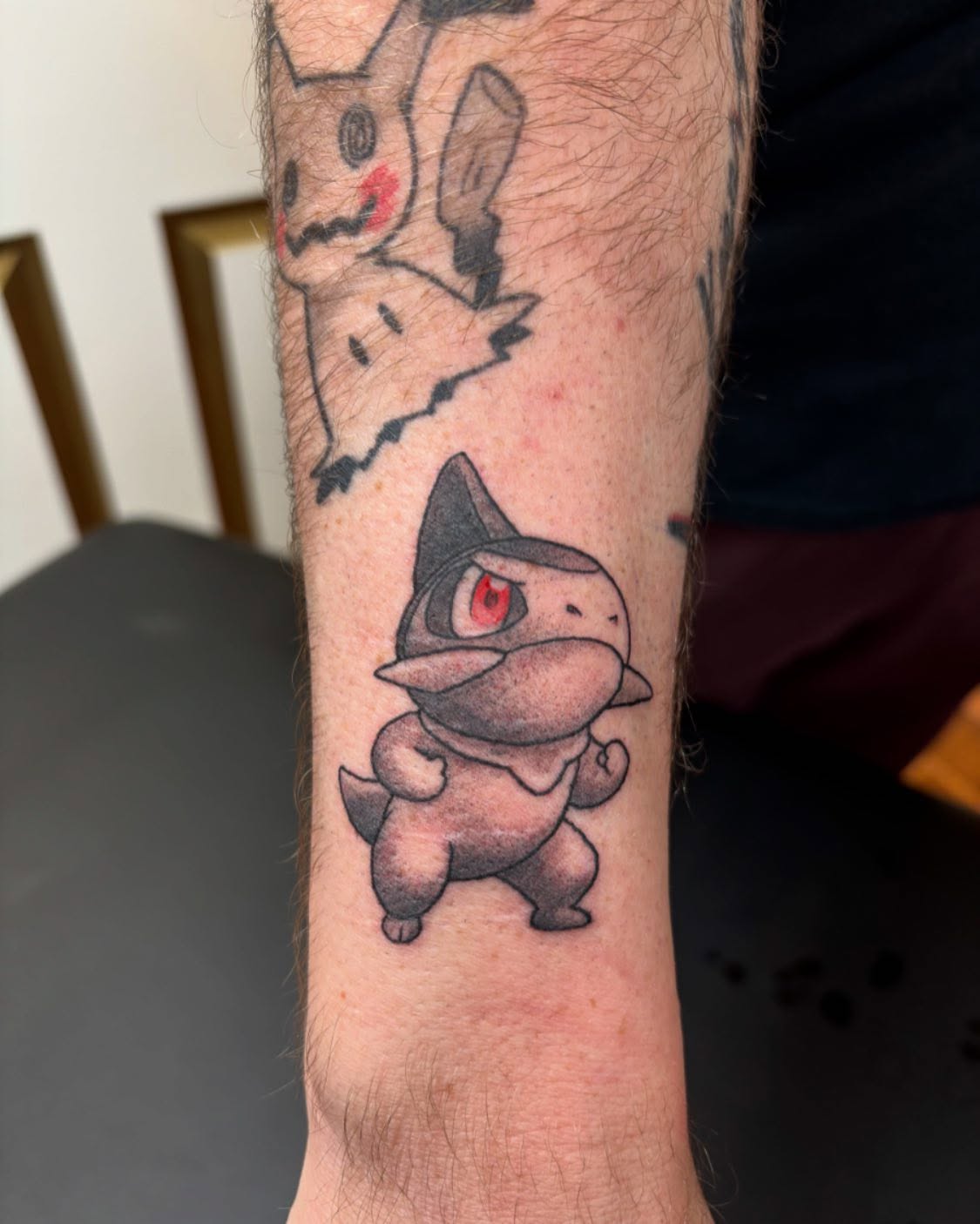 Determined lil’ Axew as an addition to a collection of black and grey and red Pokemon! (Healed Mimikyu above him also by me!) Thanks for the continued trust, Rosser ✌️ #pokemon #pokemontattoo #axew #pokemonblackandwhite #anime #animetattoo #queertattooartist #queertattooer