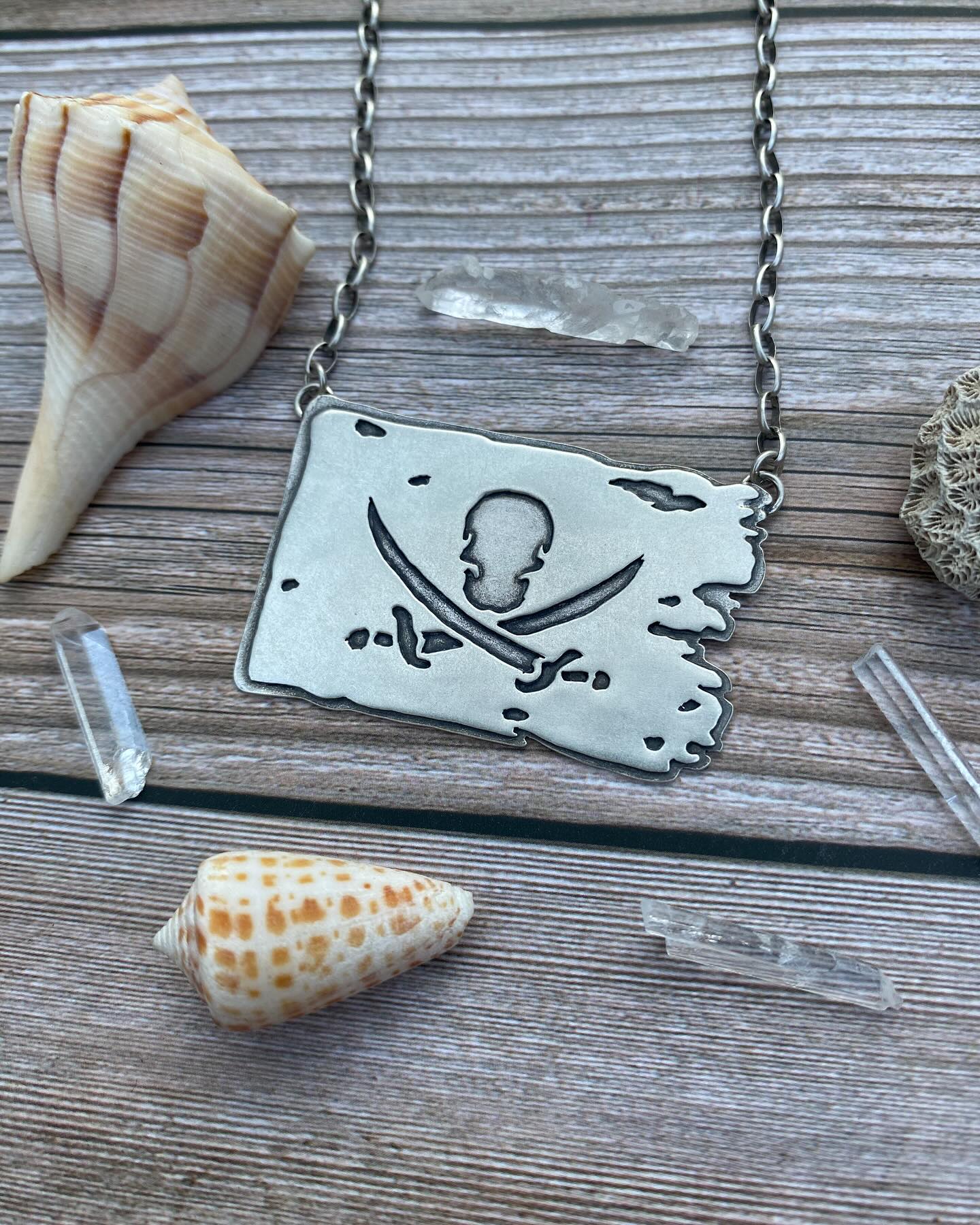 ‘Jolly Roger’ Pirate Flag 🏴☠️ This flag was flown by pirates to signal their arrival and intentions - a demand for surrender or an impending attack. 🔥☠️ There are many variations of the Jolly Roger flag, but all were meant to instill fear and intimidation and serve as a final warning. The term Jolly Roger is a reference to the French term “jolie rouge” meaning “pretty red” which was a term for a particular flag style. 🩸
.
This one of a kind handcrafted sterling silver necklace will be available tomorrow 5/25 along with all the other shark teeth stuff I’ve been posting about! ☺️✨