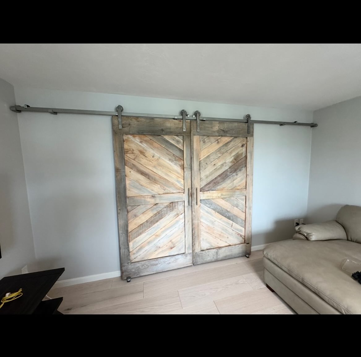 Andrea and Luis from Peabody, MA wanted to have nicely designed barn doors installed into a home office that is in a room just off the kitchen. This space will be used for Luis’s computer work and occasional home meetings and calls, so the noise and privacy concern is real in a home setting.
Semi-rustic divider doors done with a lighter reclaimed stock in an elegant angled chevron style were crafted by The Barndoorist and installed to compliment the lighter flare color scheme of the home. Note the nickel colored hardware and handles on the inside of the office space that were used. These are just like the ones used on the kitchen cabinets and drawers!
We used a special mix of Bri Wax coating which is a clear with hints of white and a grayish light wash on some portions of the blonde and light brown aged pine wood boards to create this varied palette.
When the doors were closed and tried out by Luis for the first time, he said he noticed a huge reduction in noise or sound coming from the other side where the kitchen is located. This will be perfect for the home office setting and our real wood thicker builds of doors installed with quality and care work wonderfully here!
You cannot get this from Home Depot or Amazon! And if you got it from Rustica, you have to install it yourself and pay someone who has NOT been specializing on sliding barn door creation and installation for ten solid years! We also warrantee our work.
#northofboston #ipswichma #marbleheadma #salemma #essexma #essexcountyma #capeannhome #northshoreboston #capeannma #rowleyma #newburyport #nbpt #newburyportma #amesburyma #farmhouse #beverlyma #manchesterbythesea #gloucesterma #barndoors #bostonbuilders #reclaimed #reclaimedmaterials #reclaimedmetal #art #localartist #artisan #antiquedoors #peabodyma #boston
