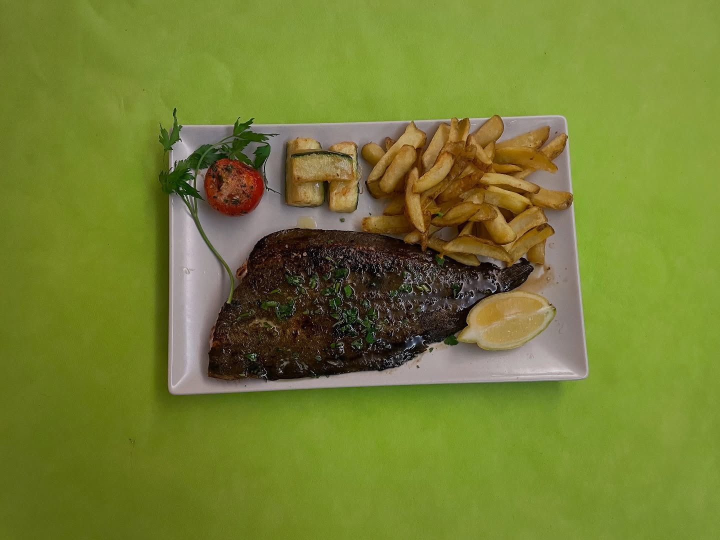 Lenguado a la plancha acompañado por una guarnición de patatas fritas, tempura de calabacín y tomate al horno.