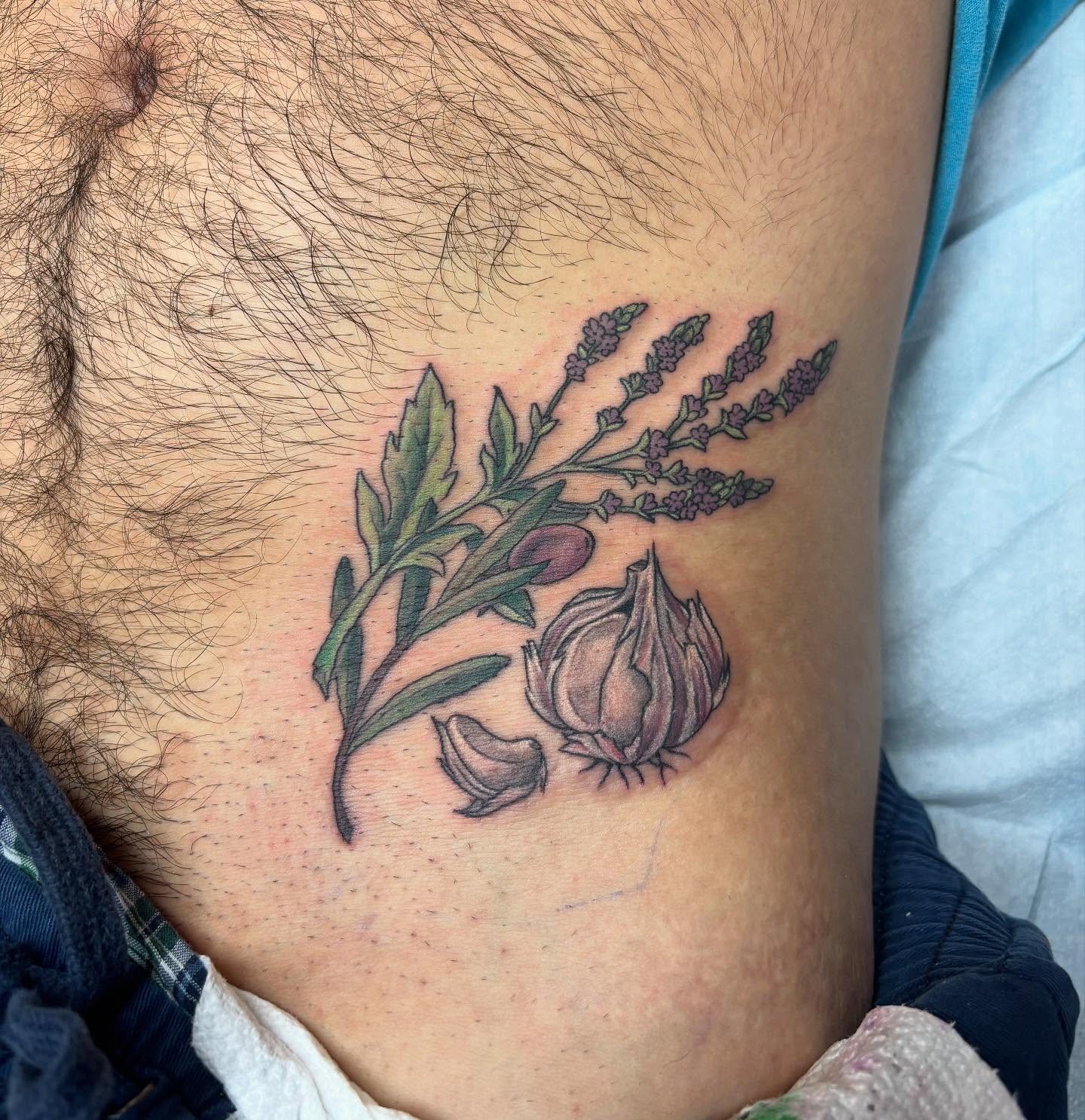 A little clutch of vervain, olive, and a bulb of garlic that was super fun. Client sat great, hip is not a fun spot to be stabbed in a bunch!! 🧄💜 #tattoo #floral #floraltattoo #garlic #vervain #olive #naturetattoo #colortattoo #queertattooartist
