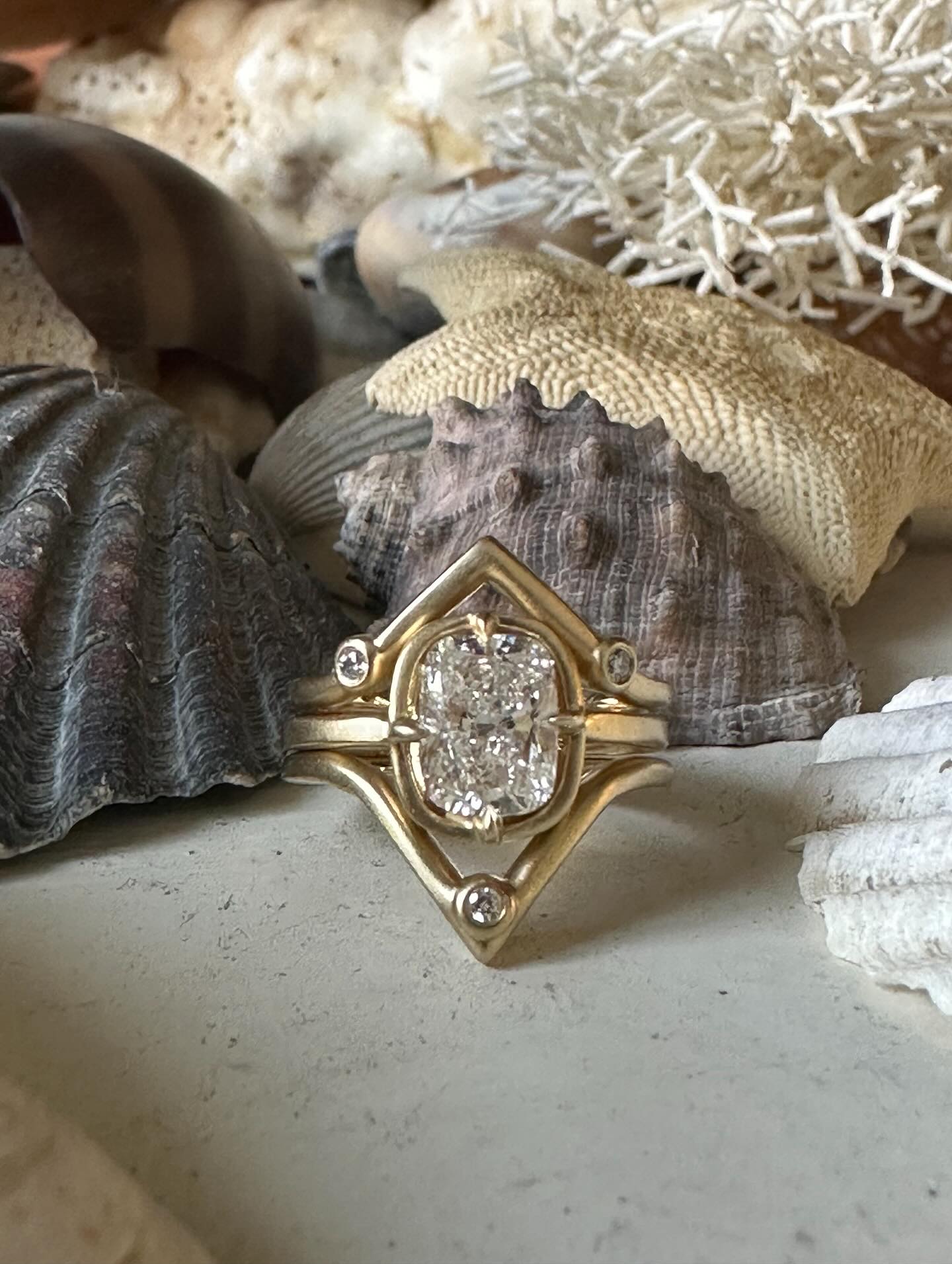 A cross country custom set made from one coast to the other. ✨ From meeting a real beauty on the beach of Rockaway to her telling her friend about me as he looked to have a special ring made for his love. Together we went back and forth, with a process of collaboration. Found this stunner of a cushion cut diamond and designed a floating setting where it is nestled in gold. My favorite piece of this project is the wedding band - it hugs and holds engagement ring, solid yet dainty with curved angles of gold and tiny round diamonds set in the number 3 as a symbol of past present and future. ✨ Paired with a hand carved wedding band where I finished with a matte gold polish to match hers. Two rings that just glow. ❤️✨ such a fun journey making these beauties for two beauties. ✨ #customjewelry#madeinnyc#nyc#katherinelincoln#engagementring#ringguard#love#engagementringset