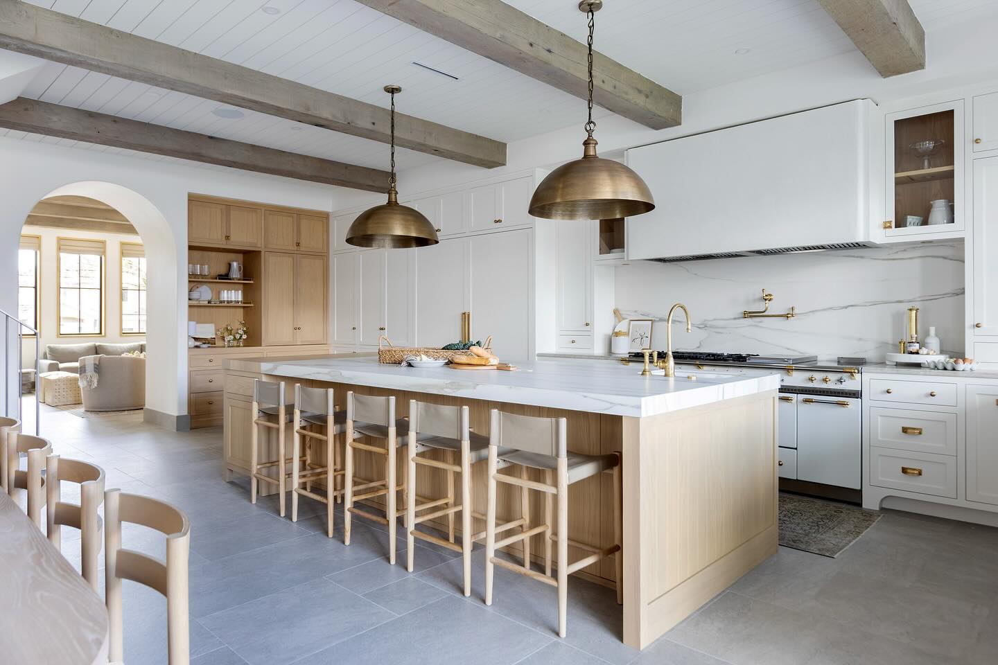 Vintage dome lights, French range, reclaimed ceiling beams and the simple curved detail on the plaster range hood. There are so many details in this lovely kitchen that bring charm to a simple colour palette.