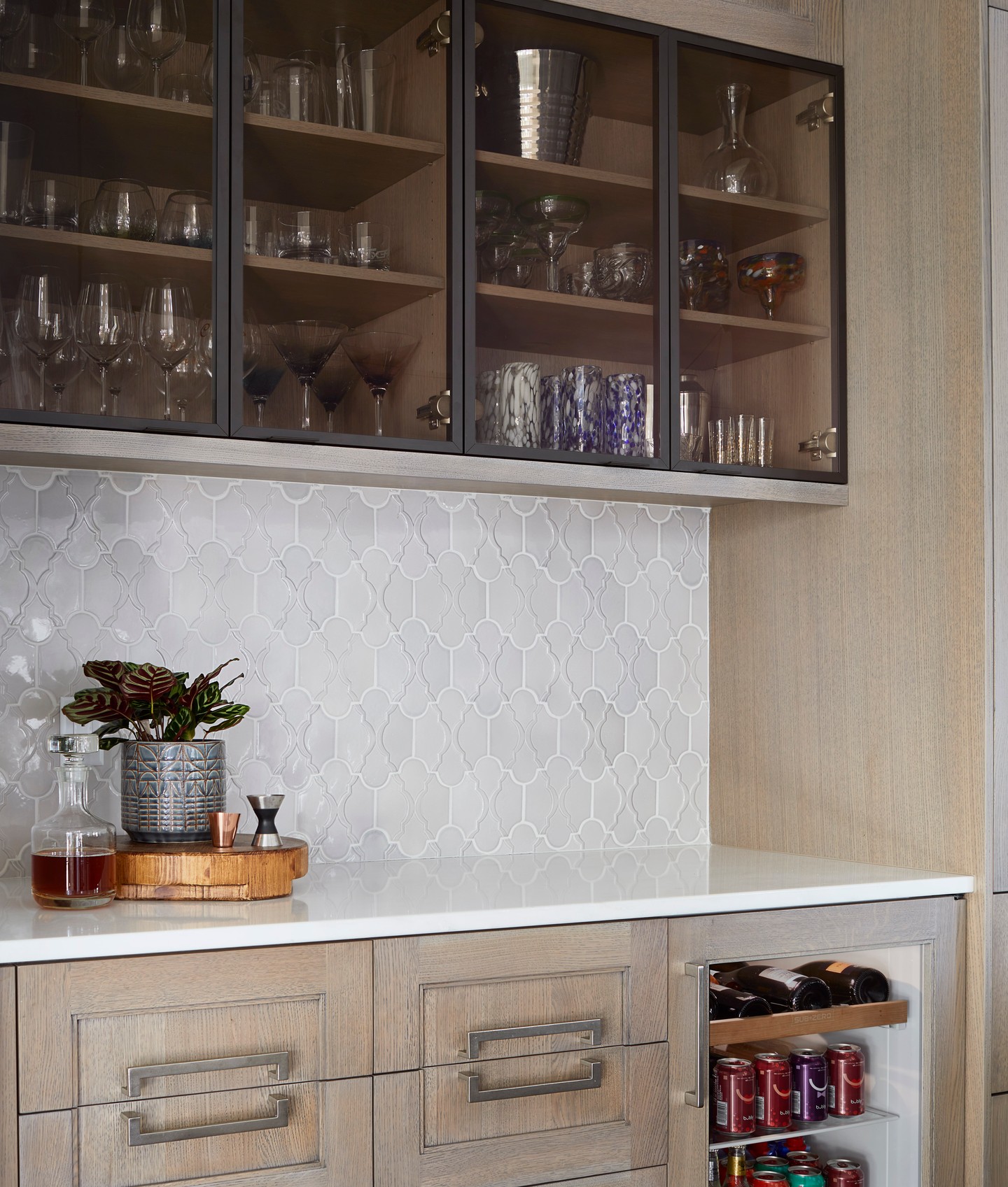 A dry bar that’s equal parts style and function. ✨ Glass-front cabinets showcase curated favorites, while the beverage fridge keeps every refreshment perfectly chilled. The warmth of the wood cabinetry paired with the intricate backsplash details creates a space that’s inviting and effortlessly beautiful.
Cheers to everyday moments made just a little more lovely.
Ready to create a space that fits your taste and lifestyle? Let’s chat — we’d love to bring your vision to life.