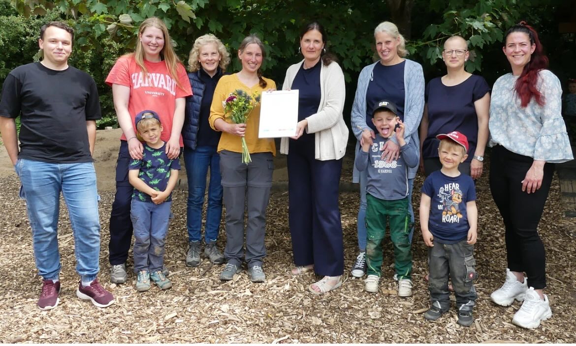 v.l.n.r Adrian Langemann, Marleen Prüßmeier, Tanja Petersen, Sandra Hachmeister, Catherine Bade, Ninja Berg, Stefanie Picard, Isabell Detering-Böker und Kinder aus dem Waldkindergarten
Strahlende Gesichter im Vlothoer Waldkindergarten „Die Käferbande“: Nach intensiver gemeinsamer Arbeit wurde die Einrichtung nun vom Paritätischen NRW mit einer Qualitätsurkunde ausgezeichnet. Der Moment war für das gesamte Team, die Kinder und Eltern etwas ganz Besonderes – schließlich steckt hinter dem Zertifikat ein jahrelanger Entwicklungsprozess, der alle Beteiligten näher zusammengebracht hat.
„Wir haben viel reflektiert, diskutiert und uns gefragt: Was können wir noch besser machen?“, erzählt Einrichtungsleiterin Sandra Hachmeister. Seit 2022 arbeitet das Team kontinuierlich an der Weiterentwicklung der pädagogischen Arbeit und an der Konzeption der Einrichtung. „An Konzeptionstagen und in Dienstbesprechungen haben wir uns immer wieder mit der Qualität in verschiedenen Bereichen beschäftigt – mit großem Engagement und viel Herzblut.“ Auch der Vorstand begleitete den Prozess aktiv.
Was in dieser Zeit entstand, ist mehr als ein Zertifikat: Es ist ein noch stärkeres Wir-Gefühl. Die enge, vertrauensvolle Zusammenarbeit zwischen Team, Eltern und Kindern hat das Gemeinschaftsgefühl nachhaltig gestärkt – ein Wert, der im Waldkindergarten eine zentrale Rolle spielt.
Die feierliche Übergabe der Urkunde übernahm Catherine Bade, Fachreferentin für Tagesangebote für Kinder beim Paritätischen NRW. Sie würdigte das Engagement und die professionelle Haltung der Einrichtung. Für das Team der „Käferbande“ ist die Auszeichnung nicht nur Anerkennung – sondern auch Motivation, diesen Weg weiterzugehen.
#kita #urkunde #auszeichnung #vlotho #kindergarten #nrw #kitas #waldkindergarten #waldkindergartenliebe #wald #kind #kindergartenkind