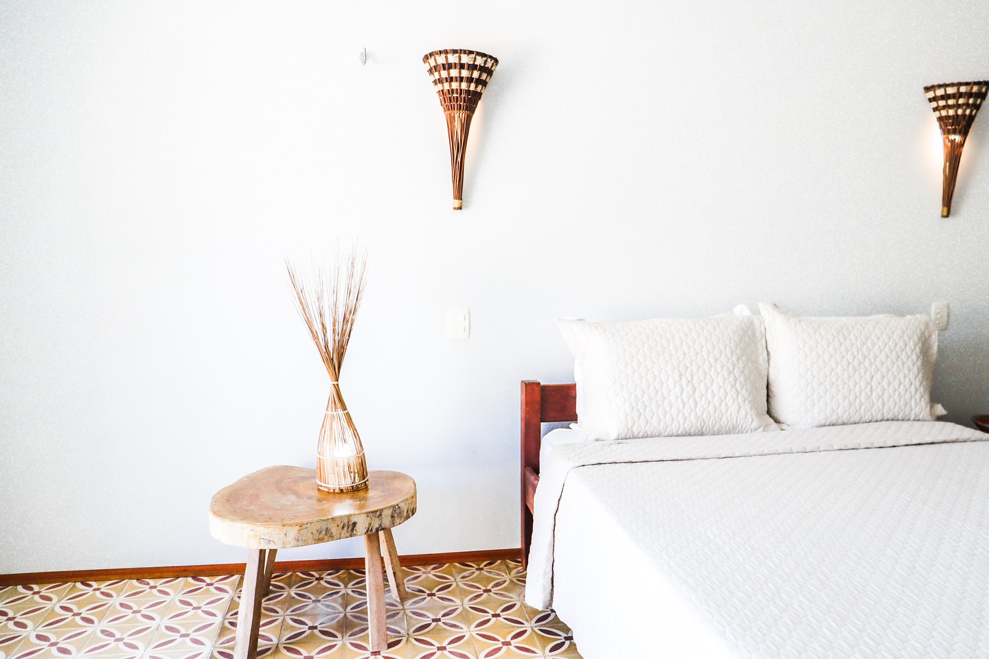 Um refúgio de serenidade e aconchego espera por você.
A cama, vestida em branco imaculado, convida ao descanso profundo, enquanto a luminária de trama natural banha o ambiente com uma luz quente e convidativa.
Cada detalhe, da textura rústica da madeira aos azulejos que contam histórias em seus padrões terrosos, foi cuidadosamente escolhido para criar uma atmosfera de paz e bem-estar.
Permita-se desconectar e recarregar as energias neste oásis de tranquilidade.