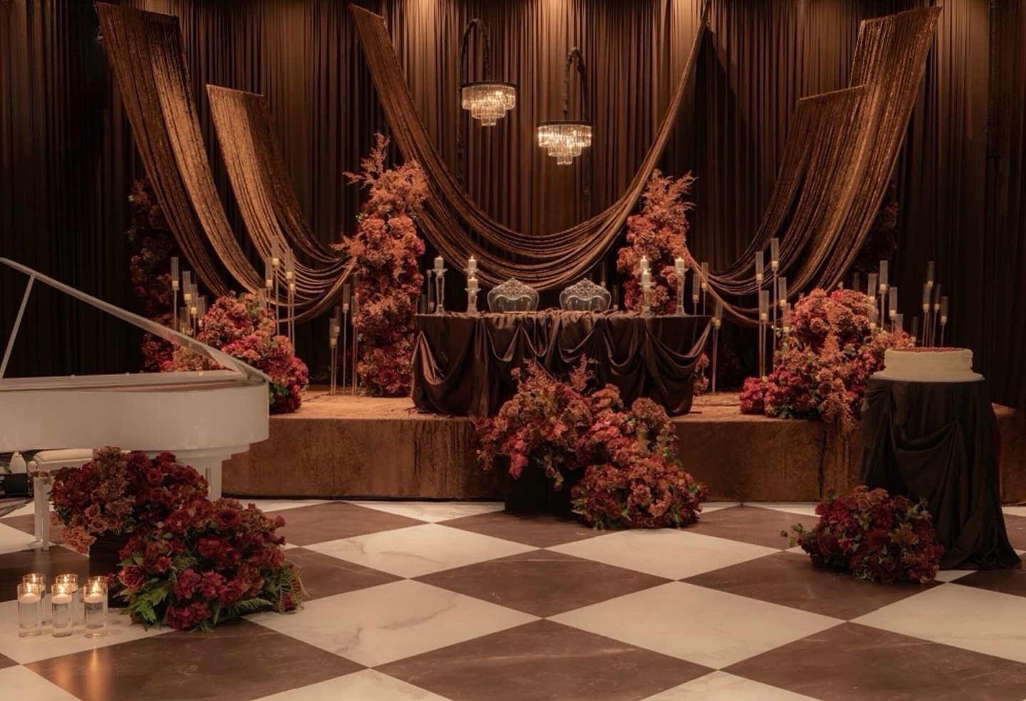 A glamorous wedding reception stage draped in rich brown fabrics, with crystal chandeliers, candlelit accents, and abundant floral arrangements in warm brown and earthy hues, all set against a striking checkered floor.
Design, Decor & Florals @universaldecor
Planning @alwaysandforeverwedding
Venue @thegrandempire_
Fabric signage @esgeeartdesign
Martini tower/name cards @ivorypeakdesign
Photos @parasrathi
Grand Piano @naman.on.keys @givemegrand
Vinyl @infiniteimpressions_
Cake @mannandcobakeshop
Photo Booth @royalebooth
Our stunning Couple @jasssibal @mannyrandhawa
#WeddingReception #WeddingDecor #ReceptionDecor #LuxuryWeddingDecor #WeddingInspiration #WeddingDesign #WeddingStyling #WeddingDetails #WeddingVibes #eventdécor