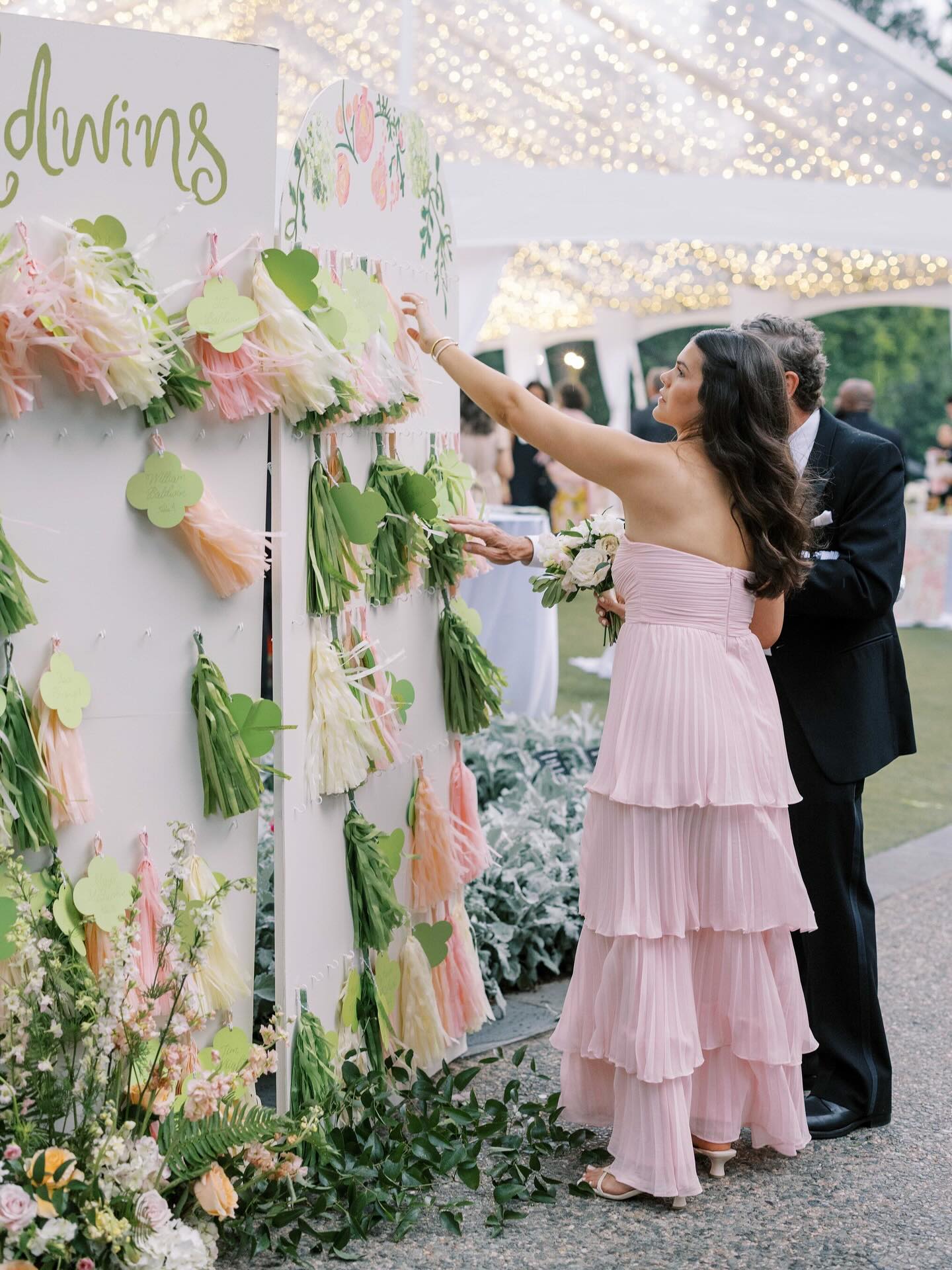 We’re all for a seating chart with a playful twist!
Guests found their seats by picking up colorful pom poms in vibrant shades of pink and green, each adorned with elegant calligraphy on quatrefoil place cards. A festive touch that doubled as a cheer to Abbey and Bobby as they made their grand entrance into the reception tent for their first dance!
Fun Fact: The bride knew she wanted to personally curate something for her wedding! After discussing wall options for the seating chart and her love for painting, we drew up a master plan to display this beautiful wall Abbey was able to freestyle paint the floral to compliment the garden style we designed throughout the wedding.
The Wedding Team✨
Planning & Design @planrevelry
Venue @dallasarboretumweddings
Photography @avery_earl
Film @reverentweddingfilms
Floral @justinesflowers
Catering @culinaryart1
Cake @cake_aholics_bakery
Band @jordankahnorchestra
Ceremony Music & Sound @sam_pistone @leforcepro
Specialty linens @nuagedesignsinc
Rentals @toptiereventrentals
Tenting @bigdpartyrentals
Stationery @gabriellewilson.designs
Day of Paper Details @mintedweddings
Hair & Makeup @ashley_mcnabb_artistry
Send Off Car @dfwvintagecars
Bridal Gown @lovelybridedallas
Groomswear @menswearhouse
#gardenwedding #dallaswedding #dallasweddingplanner #dallasweddingvenue #dallasarboretum #outdoorwedding #springwedding #seatingchart #brideandgroom #tentwedding #luxurywedding