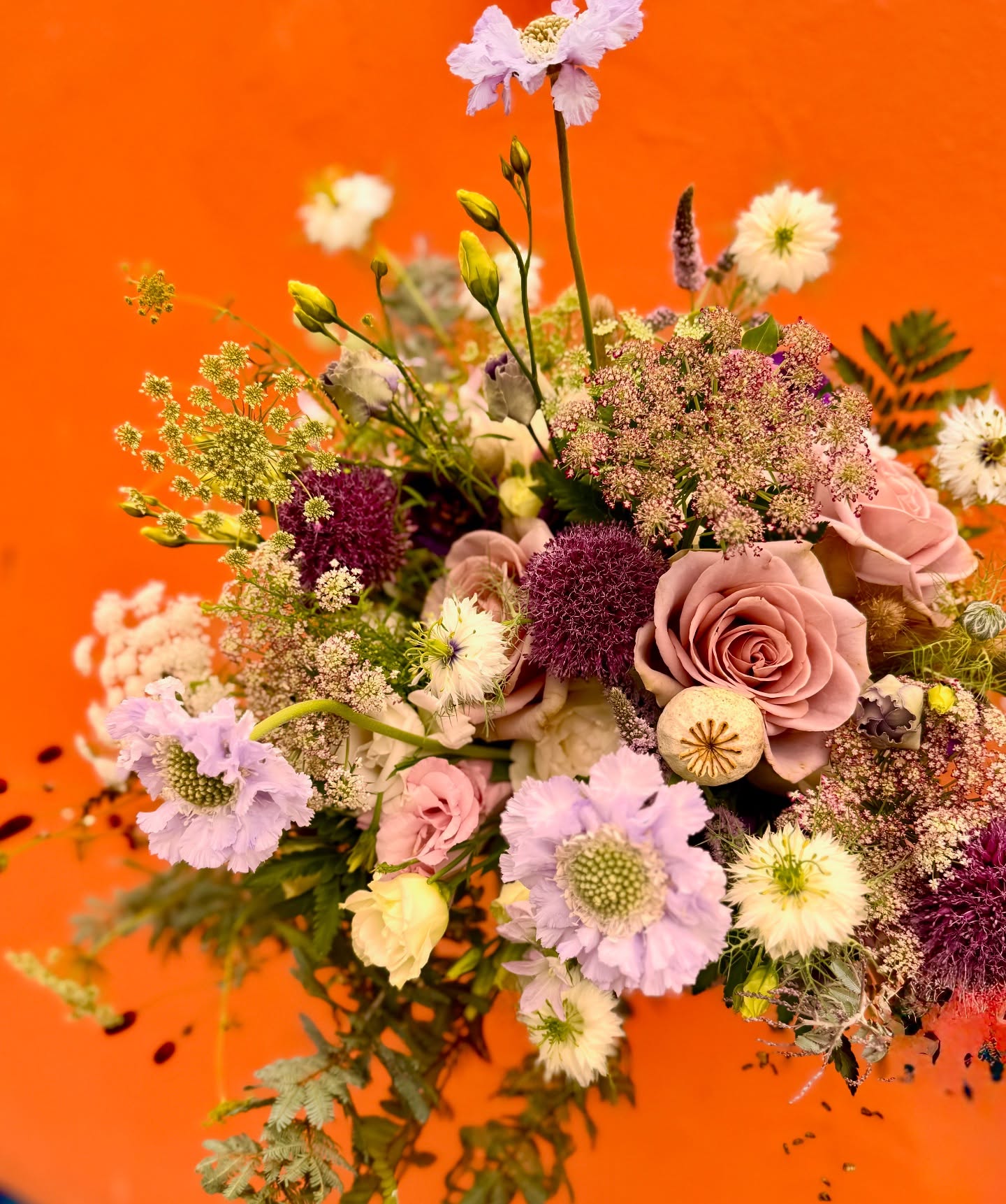 Late summer flowers are glorious for August weddings. This fabulous bridal bouquet with mixed tonal lilac, purple and pink with mixed greenery looks striking against the burnt orange backdrop. #totnesflorist #devonflorist