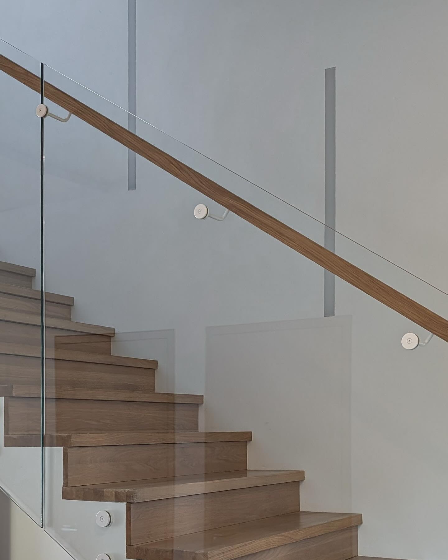 Berėmio stiklo turėklai su medžio masyvo porankiu. Stiklo ir porankio laikikliai nudažyti balta matine spalva. #vilniaustureklai #tureklai #pakopos #laiptai #gamyba #metalas #metaliniaitureklai #dizai…