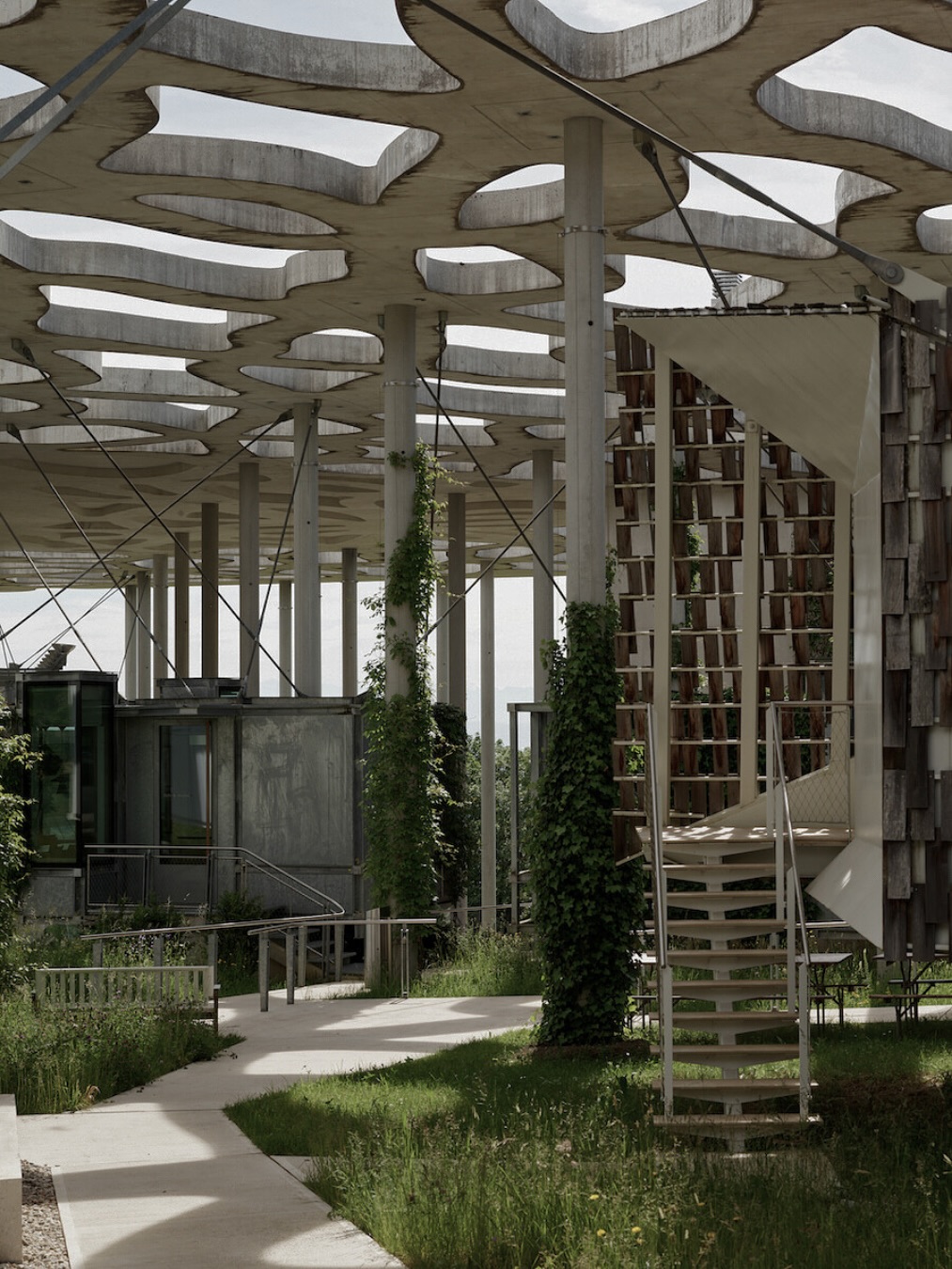 Fondation Jan Michalski pour l’écriture et la littérature — l’un des lieux culturels les plus poétiques d’Europe, où l’architecture et la nature s’unissent pour inspirer la création.
Située à Montricher, au pied du Jura, la Fondation a été créée en 2004 par Vera Michalski-Hoffmann en mémoire de son mari Jan Michalski, afin de perpétuer leur engagement commun envers ceux qui se consacrent à l’écrit.
Résidences pour écrivains et traducteurs
Imaginée comme une petite communauté abritée sous une « canopée-nuage » et entièrement entourée de nature, la Fondation accueille chaque année une quarantaine d’auteurs et traducteurs venus du monde entier. Sept modules suspendus, appelés « cabanes », offrent des conditions idéales pour commencer, poursuivre ou achever un projet d’écriture. Chaque cabine dispose d’un espace de vie avec cuisine, salle de bain et lit, ainsi que d’un espace de travail et de lecture.
La Fondation accorde une attention particulière au nature writing, un genre qui relie la littérature à la conscience écologique et aux interconnexions entre l’humain et l’environnement.
Outre les résidences, la Fondation soutient la littérature à travers des expositions, des événements culturels, une bibliothèque multilingue de plus de 80 000 ouvrages, un prix littéraire annuel et de nombreuses initiatives éducatives. C’est un lieu de rencontre entre écrivains, artistes et lecteurs — un espace où la culture reste vivante et où les idées circulent librement.
✦ Architecture
Réalisée en 2013 par les architectes Vincent Mangeat et Pierre Wahlen (Atelier Mangeat Wahlen Architectes Associés, Lausanne), la Fondation se distingue par sa grande toiture ajourée en béton, semblable à un nuage, sous laquelle s’abritent la bibliothèque, les salles d’exposition et les cabanes suspendues. L’ensemble compose un « village flottant » magnifiquement intégré au paysage forestier.