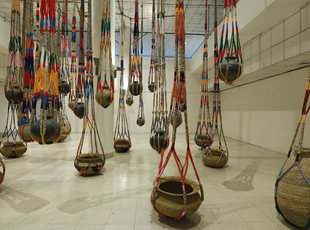 Today, we look back at ‘The Fibrous Souls, 2018–2020’ by Kamruzzaman Shadhin, featured in DAS 2020 as part of the exhibition 'Colonial Movements' curated by Diana Campbell.
Kamruzzaman Shadhin’s collaborative work interweaved strands of history that seem innocently distinct from but are in fact connected to present-day peasant conditions in South Asia. The artist invited ecological migrants residing in his village who moved from the ‘jute tracks’ of Southern Bangladesh to create a memorial reminding us of how the desire and pursuit of a commodity economy continues to transform the land that we stand on. Seventy giant shikas hang in a formation based upon the Assam Bengal Railway that operated under British India from 1892–1942. Railways were a form of connectivity that displaced people and their ways of life; their construction transformed Bengal’s lands from growing food to producing globally desired commodities (jute, indigo, opium).
The project was realised in collaboration with Gidree Bawlee Foundation of Arts. Commissioned and Produced by Samdani Art Foundation for DAS 2020. Courtesy of the artist and Samdani Art Foundation.
Photograph from DAS 2020.
@dhakaartsummit
@samdaniartfoundation
@srihatta_sylhet
@nadiasamdani
@rajeebsamdani
@dhakadiana
@rux_q
@shadhin.kamruzzaman
@gidree.bawlee
@swilin_haque
@sazzad1985
@iftekharnoor
#dhakaartsummit #samdaniartfoundation #dhaka #sylhet #art #artwork #DAS #exhibitions #contemporaryart #srihatta #artistresidency #sculpture #kamruzzamanshadhin