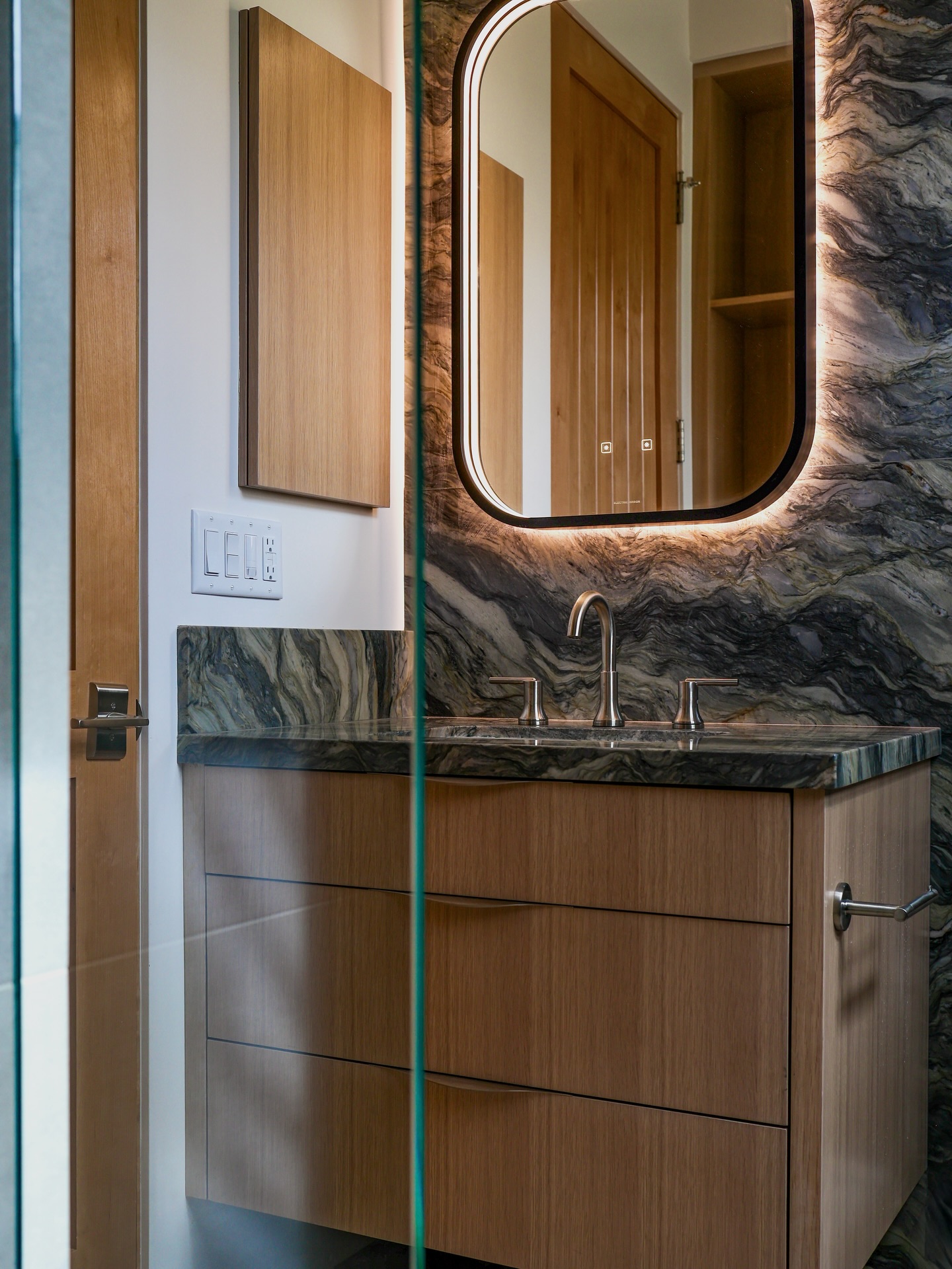 Imagine stepping into this bathroom at a house party! It's mesmerizing.
We especially like the matching medicine cabinet and the backlit mirror casting light into the wall, like flames onto the stone.
photo by @b.ritt.back