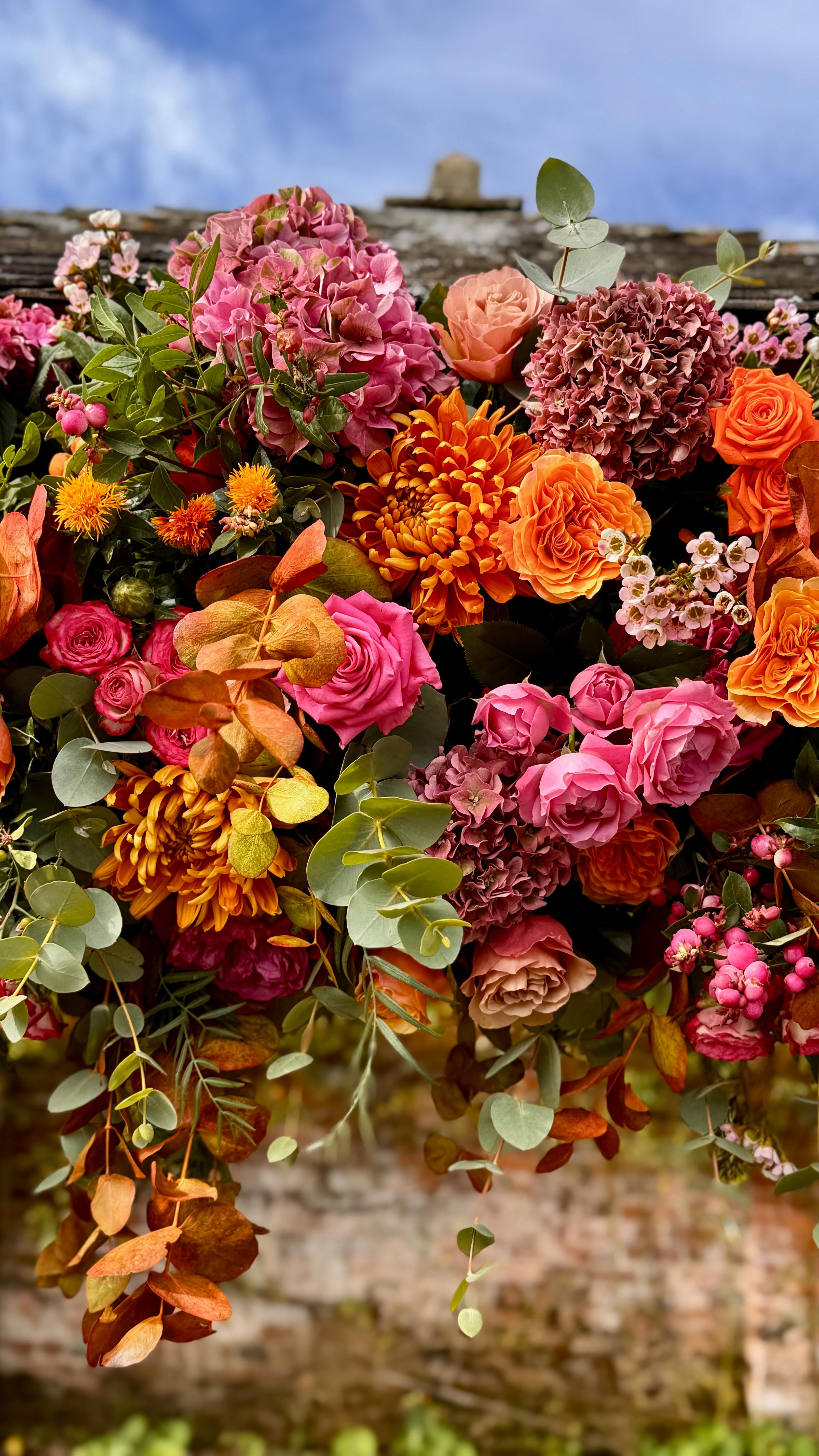 @burtonfest2025 is the name that Gemma & Jamie Burton branded for their wedding celebrations at @estatekingston - Saturday, 6th September 2025. Bold colourful hot pink and orange splashed throughout the Walled Garden and marquee in the Rose Garden. In addition to the wedding, it was also Donâs birthday đand as usual the sun shone with a delightful autumnal glow albeit quite windy. Thank you @jodie_kingstonestatedevon for solving the blustery drape situation on the gazebo by tying a knot at the base of the fabric. The floral meadow arrangements on the ceremony aisle lawn were reused through the trestle tables in the clear span marquee. The gazebo design remained in situ for use in the evening when guests enjoyed a cocktail party after the wedding breakfast.
#totnesflorist #devonflorist #naturallyabundant #devonwedding #timelessweddings #countrywedding #englishgardenwedding #luxeweddings #luxetablescapes #flowerlover #weddingfest