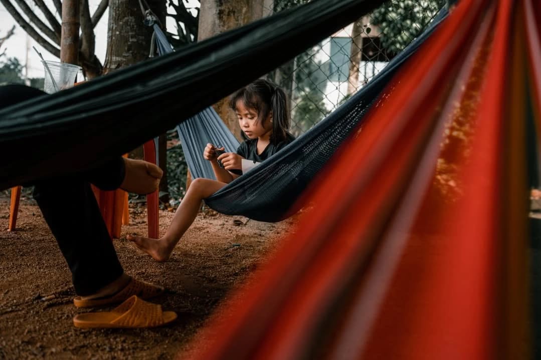 Cà Phê Võng, happiness is at the hammock café
At the side of the road, a tin, tarpaulin, or straw roof provides thick, comforting shade. Beneath it, immersed in this semi-darkness, hammocks swing gently. Made of canvas or netting, they are complemented by a small plastic table. On this table, an iced coffee, a fresh coconut, or sugarcane juice accompanies the refreshing breeze and invites drowsiness. Muffled conversations, occasional snoring, and often discreet smiles. Places for socializing as much as for resting, Cà Phê Võng are everywhere in southern Vietnam. These hammock cafés are my little everyday paradises.
_______
Cà Phê Võng, le bonheur est au café-hamac
Au bord de la route, un toit en tôle, en bâche ou en paille offre une ombre épaisse, réconfortante. Dessous, plongés dans cette pénombre, des hamacs suspendus se balancent. En toile ou en filet, ils sont accompagnés d'une petite table en plastique. Sur cette table, un café glacé, une noix de coco ou un jus de canne à sucre accompagne la brise rafraichissante et invite à la somnolence. Des conversations feutrées, quelques ronflements parfois et des sourires discrets souvent. Lieux de sociabilité autant que de repos, les Cà Phê Võng sont partout dans le Sud du Vietnam. Ces café-hamac sont mes petits paradis quotidiens.