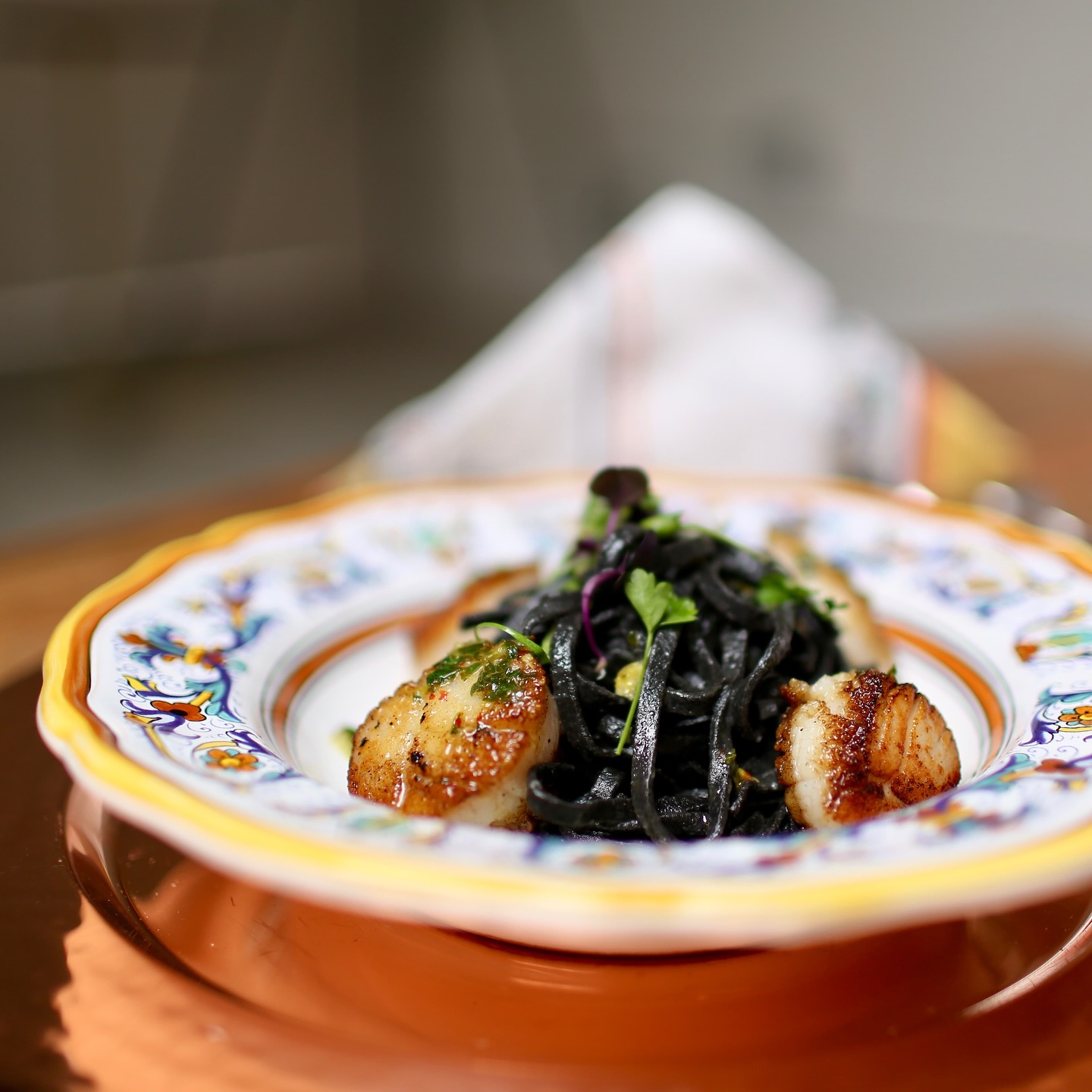 My Recipe for Squid Ink Scallop Pasta! 🦑 One of my end-of-summer favorites! Check out the recipe below!
Ingredients
12 oz linguine or spaghetti
1 lb large sea scallops, side muscle removed
2-3 sachets squid ink (about 8g total)
3 tablespoons olive oil
4 cloves garlic, minced
1/2 cup dry white wine
1/2 cup heavy cream
2 tablespoons butter
1/4 cup fresh parsley, chopped
Salt and freshly ground black pepper
Lemon wedges for serving
Instructions
Prepare the pasta water: Bring a large pot of salted water to boil for the pasta.
Prep the scallops: Pat scallops completely dry with paper towels and season both sides with salt and pepper. Let them come to room temperature.
Cook the pasta: Add pasta to boiling water and cook according to package directions until al dente. Reserve 1 cup pasta water before draining.
Sear the scallops: Heat 2 tablespoons olive oil in a large skillet over medium-high heat. When oil shimmers, add scallops without overcrowding. Sear for 2-3 minutes per side until golden brown and cooked through. Remove to a plate.
Make the sauce: In the same skillet, reduce heat to medium. Add remaining olive oil and minced garlic, cooking for 30 seconds until fragrant. Add white wine and let it reduce by half.
Add squid ink: Stir in the squid ink, mixing well to combine. Add cream and simmer for 2-3 minutes until slightly thickened.
Combine: Add the drained pasta to the skillet with the squid ink sauce. Toss with butter and a splash of pasta water to create a silky coating. Season with salt and pepper.
Finish and serve: Return scallops to the pan briefly to warm through. Garnish with fresh parsley and serve immediately with lemon wedges.