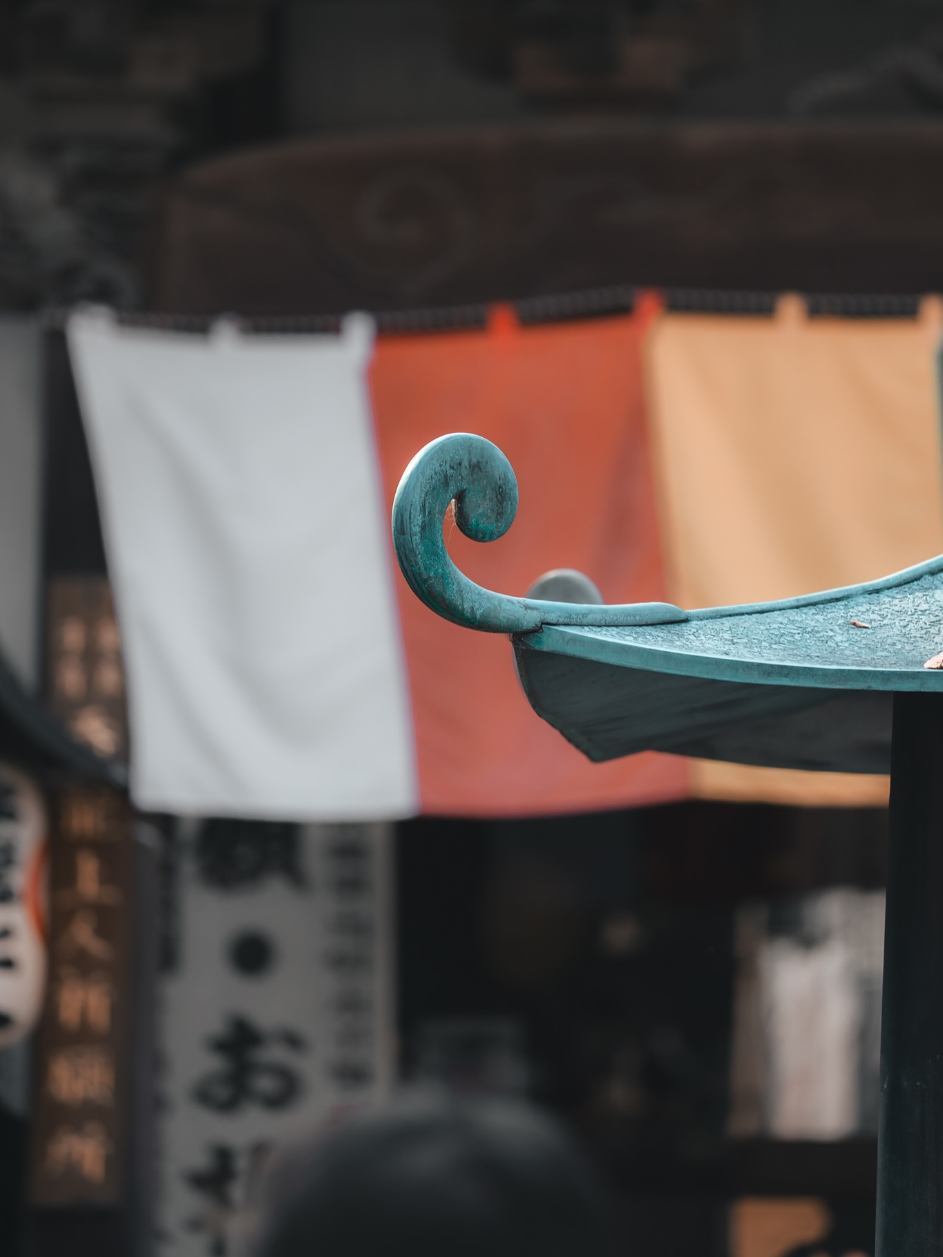 Kawagoe, auch bekannt als “Little Edo”, ist einer dieser Orte, an denen Ihr plötzlich das Gefühl habt, in eine andere Zeit versetzt zu werden. Nur eine halbe Stunde von Tokyo entfernt und trotzdem eine ganz andere Welt. Enge Gassen, Holzhäuser, Tempel, bunte Stoffbanner im Wind und der Duft von Räucherwerk, all das macht die Stadt besonders.
Am besten startet Ihr im Viertel Kurazukuri no Machinami. Dort stehen die alten Lagerhäuser mit ihren dicken Wänden noch immer. Dazwischen findet Ihr kleine Läden mit Süßigkeiten, Matcha und Streetfood. Lasst Euch einfach treiben und probiert unbedingt ein paar der berühmten Süßkartoffel-Snacks.
Wenn Ihr Tempel mögt, lohnt sich ein Besuch beim Kitain-Tempel. Ihr könnt Räucherstäbchen entzünden, eine kurze Pause einlegen oder einfach die Atmosphäre auf Euch wirken lassen. Die bunten Fahnen und die vielen ema-Holztafeln mit Wünschen der Besucher sorgen für eine besondere Stimmung.
Kawagoe lebt auch von den kleinen Momenten. Ein Paar in traditionellem Kimono, das langsam durch die Gassen geht. Der Klang der Tempelglocke, der durch die Luft schwingt. Alte Gaslaternen, die in der Nachmittagssonne lange Schatten werfen.
Für einen Tagesausflug ist Kawagoe perfekt. Ihr entkommt dem Trubel Tokyos, ohne weit zu reisen, und bekommt eine schöne Mischung aus Geschichte, Tempeln, Essen und lebendigen Straßen. Also packt die Kamera ein, zieht bequeme Schuhe an und lasst Euch einen Tag lang durch Little Edo treiben.
#kawagoe #littleedo #japantrip #japanreise #japanvibes #japantravel #tokyoescape #kurazukuri #kitain #kawagoedaytrip #japanphotography #traveljapan #visitjapan #japanstreetphotography #focusfernweh #reiseblog #japan2025