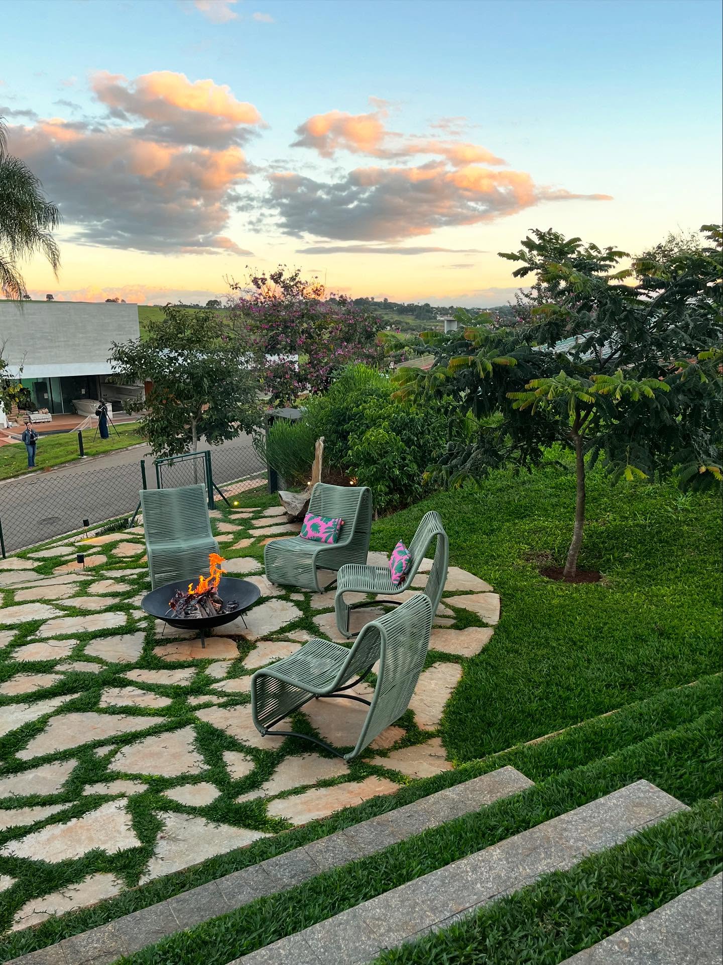 Uma Cassia Rosa (Cassia grandis) para sombrear esta área com lareira externa - o lugar perfeito para curtir o pôr do sol. Ao fundo, alguns pés de café remetendo à história deste condomínio que era uma plantação de café antes, junto com as escultóricas carquejas ((Baccharis trimera) e Orelha de Urso Branca (Tibouchina radula).
.
A tree Cassia grandis provides shade for this outdoor fireplace area—the perfect place to enjoy the sunset. In the background, some coffee trees hint at the history of this condominium, which was once a coffee plantation, along with the sculptural carquejas Baccharis trimera and Tibouchina radula