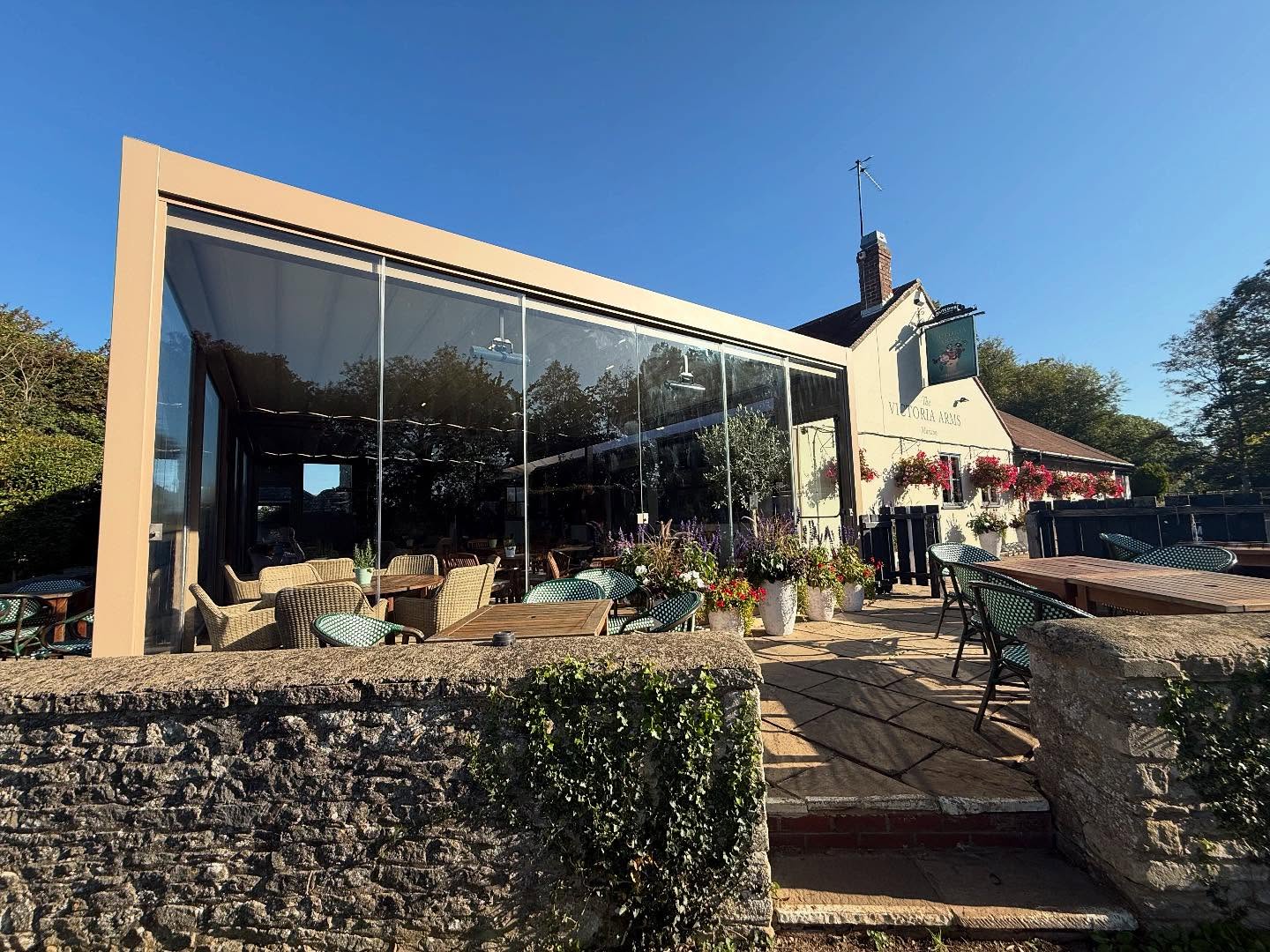 An impressive addition to this very popular Oxfordshire pub - adding a glass sided Corradi Maestro system with retractable roof complete with a mix of hardwood Blewbury furniture, and traditional basket style weave Maldives chairs.
A very special spot to enjoy lunch or dinner and soak in the views.
#roofsystem #retractableroof #pergola #gardenroom #pubgarden #pubdesign #countrypub #commercialfurniture #contractfurniture #pubfurniture #hospitalitydesign #restaurantdesign