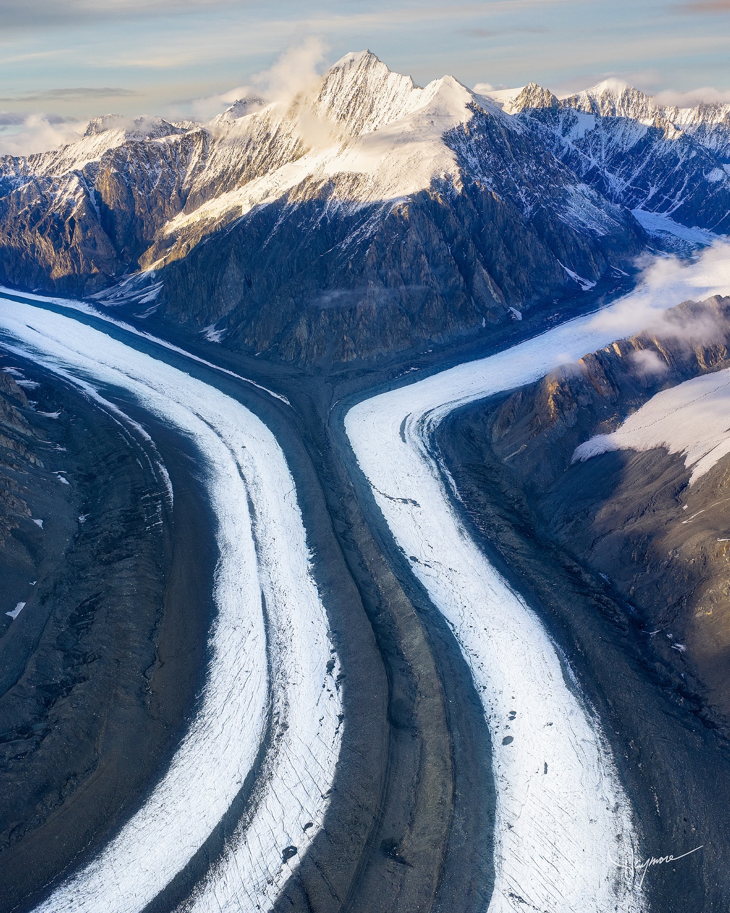 On the last day of our Aerial Alaskan Adventure workshop, we took a helicopter tour and landed on this stunning glacier, wrapping around the distant peak and converging to form a mega glacier.
It was surreal climbing to 12,000 feet, where the air was thin and temperatures plummeted. Our finders froze stiff and we had a hard time gripping our cameras. After the birds eye view, we landed and walked its surface, touching and feeling the rocks the massive ice flow had pushed for miles.