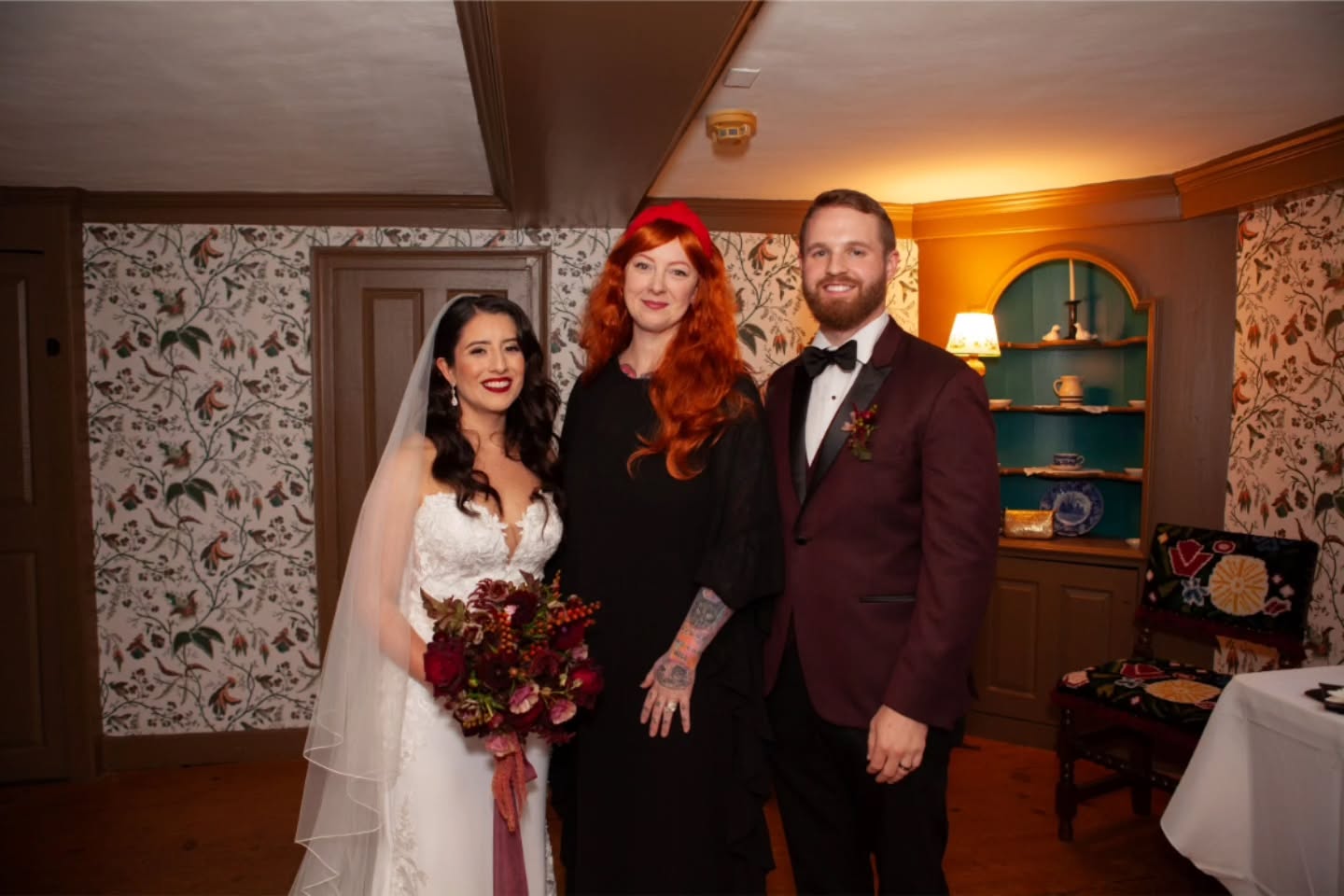 Lia & Dane traveled from Connecticut for an intimate wedding at the House of the Seven Gables here in Salem – a place already entwined with their love story. It was the first spot they visited on their very first trip to Salem, and Dane even gifted Lia a copy of the novel from the museum shop as his first Christmas present to her! Beyond their personal connection, the Gables’ deeper history made their location choice all the more meaningful – once serving as a settlement house that welcomed immigrants and fostered community, it resonated powerfully with Lia’s Peruvian roots and the couple’s shared values.
When the skies opened up that day, the rain only added to the magic! We moved the ceremony indoors with chairs in a half circle… and the moody light and soft sound of rain outside gave everything a sacred stillness.
Their ceremony was romantic, whimsical, and a little witchy, yet still timeless and elegant. We included their Love Story, personal vows, and custom “I Do” vows, along with a reading of Pablo Neruda’s “Sonnet XVII” from One Hundred Love Sonnets – read in English by me and in Spanish by Lia’s sister. The highlight was their handfasting, performed with a rope acquired in Peru, the first place they traveled together. Their cord – a handwoven textile of black, white, and red alpaca yarn – was made in the Andes, where weaving is more than art; it’s a sacred act of connection and an offering of reverence to Pachamama. And here’s the beautiful part: rain on a wedding day is said to bring good luck… but a handfasting in the rain is EXTRA lucky, because a wet knot is harder to untie!
Dane and Lia sealed their union walking out to “Come and Get Your Love” by Redbone, followed by empanadas, cake, and a lovely dinner at @finzseafoodsalem. It was a day rich with meaning, culture, and heart – one that truly felt blessed from start to finish. I was so honored to create and share their dream ceremony! 🖤
🏠 @h7gables
📸 @thingstodoinsalem
🎥 @lollieweddingfilms
💐 @heliosfloral
#salem #salemmassachusetts #salemwedding #salemweddingwitch #weddingwitchofsalem #salemweddingofficiant #houseofthesevengables #intimatewedding #smallwedding #handfasting #pachamama