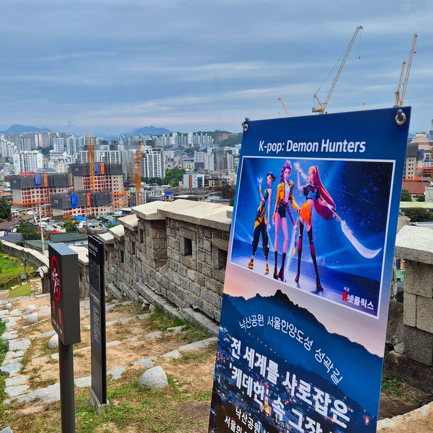 “That romantic walk from K-Pop Demon Hunters 💕 where Rumi and Jinu had their date scene is right here at Naksan Fortress Wall Trail!”
Walk the same path overlooking Dongdaemun Gate and the glowing skyline of old Seoul.
This trail is part of the Seoul City Wall (Hanyangdoseong), built in the 14th century to protect the capital.
Today, it’s one of the most scenic city walks, peaceful, historic, and cinematic.
At the top, you’ll find hillside cafés with panoramic city views ☕
And when you come down, explore Ihwa-dong and Hyehwa, filled with murals, art studios, and hidden local gems.
If you’re visiting Seoul, this is a must-see, a real-life K-drama location where history meets modern Seoul. 🌙