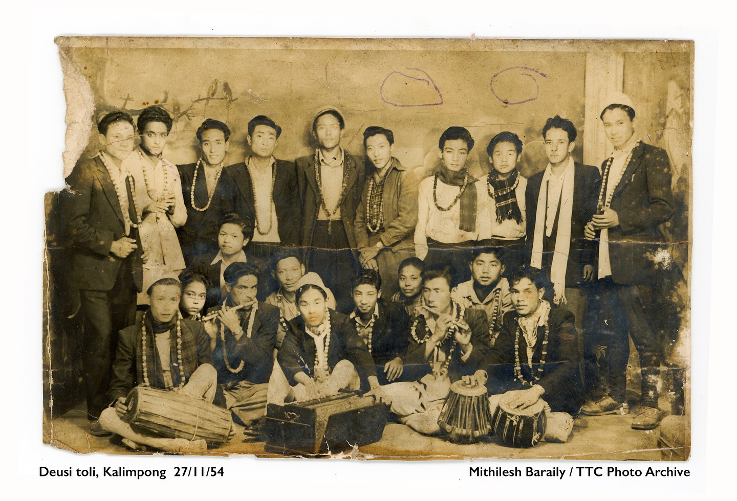 TIHAR GREETINGS TO ALL
No Tihar celebration is complete without a lively Deusi Bhailo group!
Deusi toli, Kalimpong * 27/10/54
Photo : Mithilesh Baraily / TTC Photo Archive
Rooted in the legends of King Bali and the blessings of Goddess Laxmi, Deusi and Bhailo are more than songs they’re stories of generosity, unity, and joy. Each verse carries laughter, blessings, and the rhythm of togetherness that lights up our hills every Tihar.
Beyond entertainment, Deusi–Bhailo strengthens social bonds and cultural identity, especially in the hills where migration and modernization often challenge community traditions. It remains one of the most joyful, inclusive, and participatory aspects of the Tihar festival.
The Confluence Collective’s digital archive safeguards a growing collection of photographs from the Darjeeling Hills and Sikkim, offering an unfiltered glimpse into the region’s rich history, culture, and everyday life. Drawing from personal, institutional, and private archives, the collection explores themes of belonging, memory, and identity crucial to understanding the social, cultural, and political fabric of the hills. By reclaiming narratives and centering local voices, TCC challenges colonial frameworks and reshapes how Himalayan histories are seen, told, and remembered.