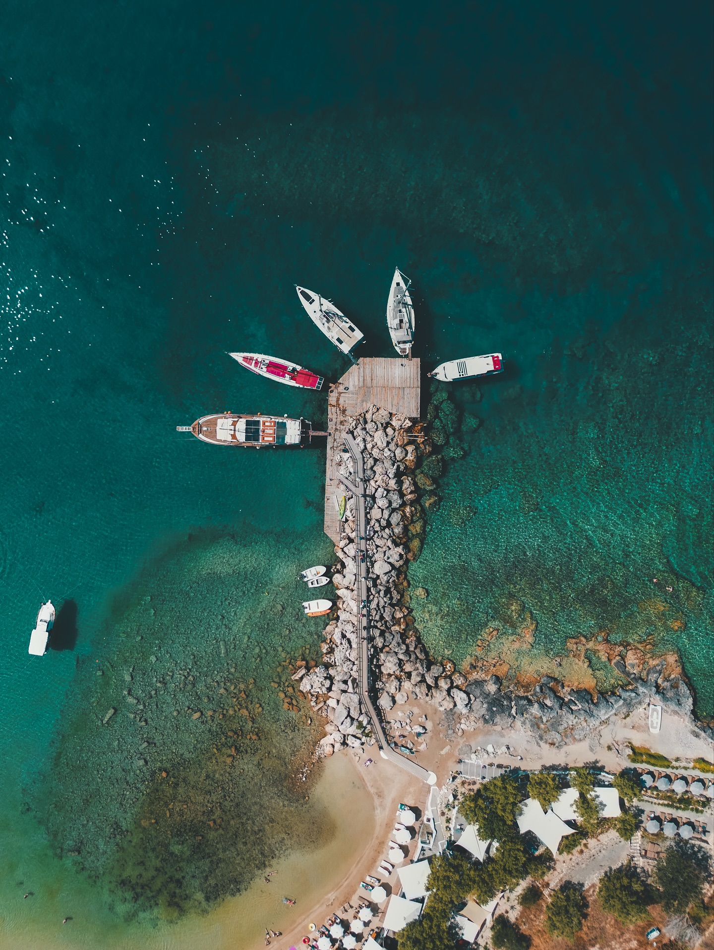 Lindos gehört zu diesen Orten, die man einmal sieht und nie wieder vergisst. Die weißen Häuser schmiegen sich an den Hang, darüber thront die alte Akropolis mit einem Blick, der weit über die Ägäis reicht. Unten schaukeln Boote in der türkisfarbenen Bucht, während sich in den Gassen das Leben gemächlich abspielt.
Wer durch Lindos läuft, spürt sofort diese besondere Mischung aus Geschichte, Sonne und Gelassenheit. Es duftet nach frisch gebackenem Brot, irgendwo klirrt Geschirr aus einer Taverne, und in den kleinen Läden stapeln sich handbemalte Keramiken, Stoffe und Schmuckstücke, die aussehen, als hätten sie schon ihre eigenen Geschichten erlebt.
Die Stufen hinauf zur Akropolis verlangen etwas Kondition, aber der Aufstieg lohnt sich. Von oben öffnet sich der Blick auf das Meer, das in allen erdenklichen Blautönen schimmert. In solchen Momenten versteht man, warum Lindos kein Ort ist, an dem man etwas abhaken möchte. Hier geht es darum, zu bleiben, zu beobachten, zu atmen und einfach da zu sein.
Zwischen den weißen Mauern findet man immer wieder kleine Plätze im Schatten, eine Katze auf der Mauer, einen Händler, der geduldig seine Waren sortiert. Alles wirkt entschleunigt und unaufgeregt, fast so, als würde die Zeit hier anders ticken.
Und wenn die Sonne langsam sinkt, taucht sie die Felsen, die Boote und die Dächer in dieses goldene Licht, das Lindos jeden Abend in eine Bühne verwandelt. Dann wird klar, warum dieser Ort so vielen im Gedächtnis bleibt: weil er still ist und doch alles erzählt, was man vom Mittelmeer erwartet.
#lindos #rhodos #greece #greekislands #visitgreece #travelgreece #griechenland #aegaeis #fokusfernweh #reiseblog #drohnenfotografie #reiseinspiration #travelphotography #reiselust #greecevacation #rhodesisland #travelgram #wanderlust #beautifuldestinations #droneview #dronephotography #mediterraneanvibes #greeksummer #greekarchitecture #islandlife #summerfeeling