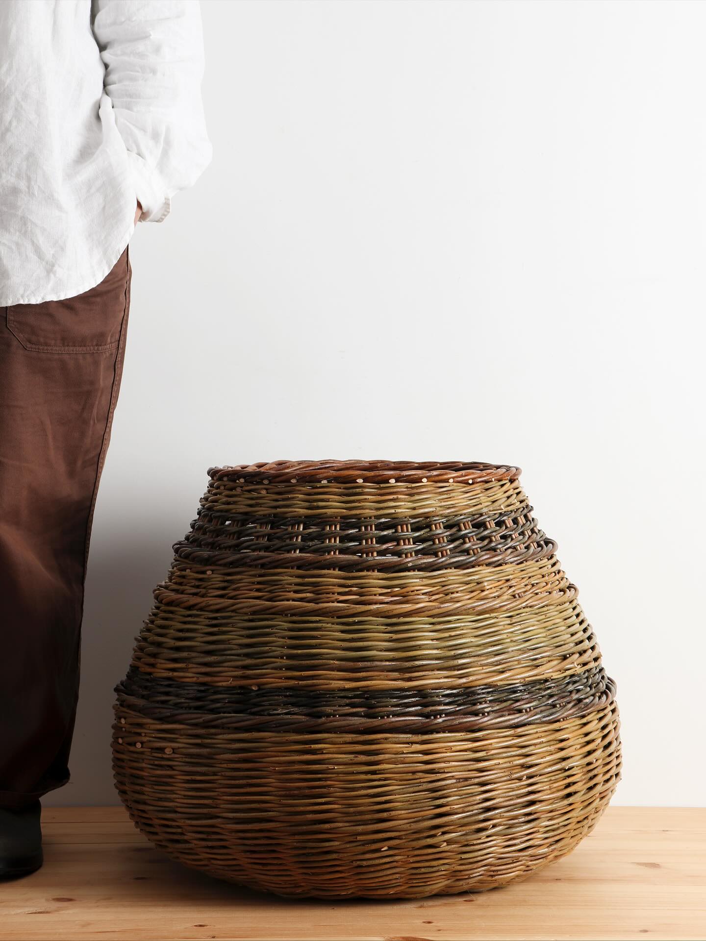 This large contemporary basket, woven with different varieties of our sustainably-grown willow, is the final piece I made for our upcoming collection. I am particularly fond of this one, with its subtle texture and some lovely contrasting colours.
It is one of a range of larger baskets I’ve made, where I have worked with the curved forms I continue to be drawn to. I have come to realise I find great enjoyment in playing with the many variations that can be found within one silhouette and style, becoming familiar whilst simultaneously finding new layers of discovery is what sustains my interest in the work.
Sarah