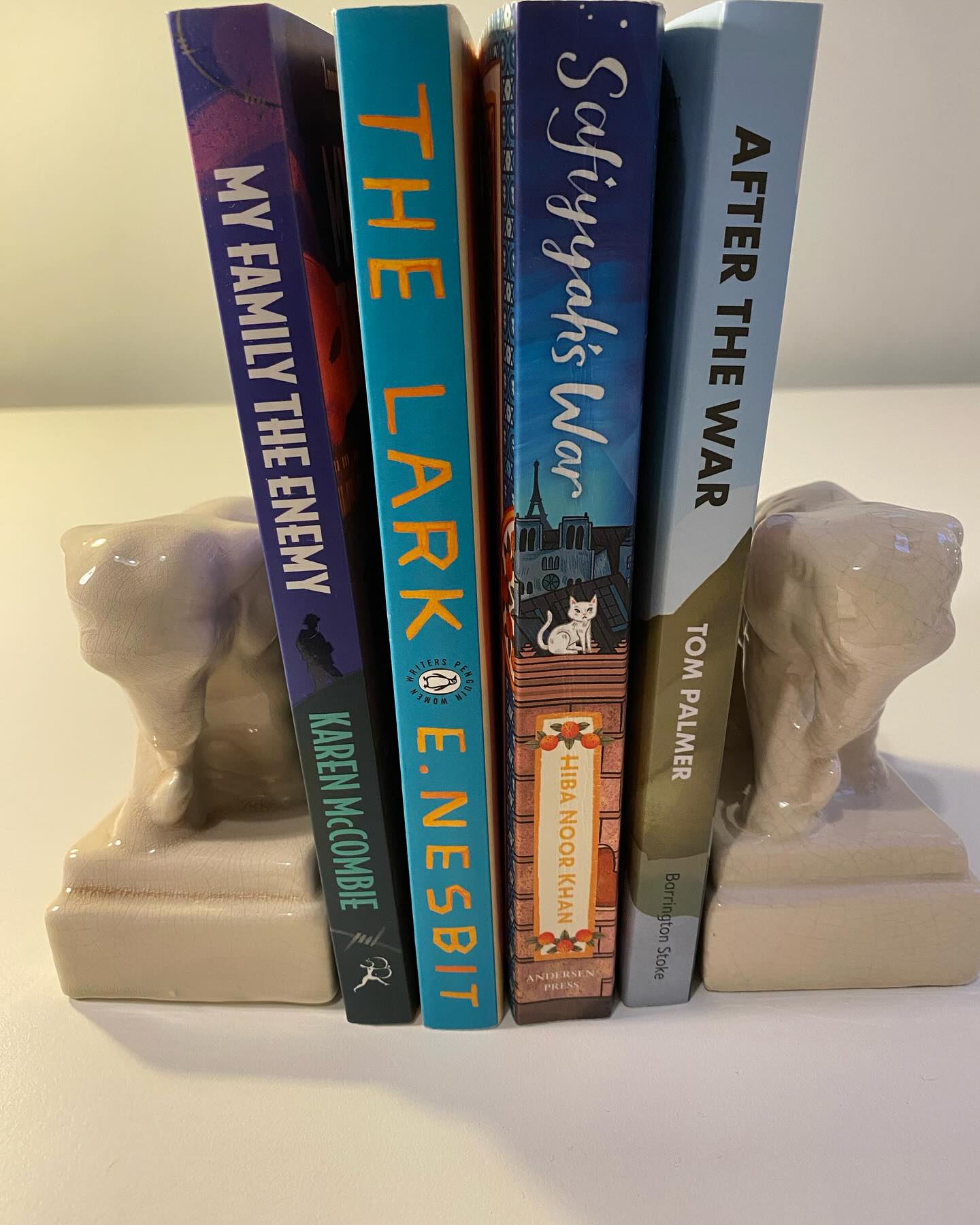 Four books I’ve really enjoyed recently. And I’ve realised all four are about war and its aftermath, from very different perspectives.
MY FAMILY THE ENEMY, by @karenmccombie, published by @bloomsburychildrens, tells the story of ten-year-old Fred, living in north London during the First World War. Fred’s father was born in Germany and is arrested and interned in nearby Alexandra Palace, along with thousands of other ‘enemy aliens’. The story follows Fred’s family and school friends as they deal with the dramas, hardships, opportunities and tragedies the war brings. It’s rooted in the history of the local area, and it’s a gripping and fascinating story.
THE LARK by E. Nesbit also starts in 1914, but then skips to 1919, when orphaned cousins Jane and Lucinda finally leave boarding school, only to find their guardian has gambled away their inheritance and left them to earn their own livings, something they never expected to have to do. I was drawn to this book, reissued by @penguinukbooks, as I adore E.Nesbit’s children’s books but had never read any of her books for grown-ups. This has a feel of I Capture the Castle about it; it’s charming and fun, but shot through with the shadow of WW1 and how it devastated people’s lives and futures. I read it on holiday and it was a perfect holiday read.
SAFIYYAH’s WAR, by @hibanoorkhan1, published by @andersenpress, set in 1940 Paris, is the story of Safiyyah and her family who live at the Grand Mosque of Paris. Safiyyah slowly becomes aware of the underground resistance work being done by her parents and their friends to help Jews escape the Nazi-occupied city. Persuading them to let her help, she gradually becomes involved in more and more risky work. This is a heart-in-mouth story of incredible bravery, based on true events. It’s wonderful that this little-known history is now part of WW2 children’s literature.
AFTER THE WAR by @tompalmerauthor, pub by @barringtonstoke, is about child survivors of concentration camps brought to the Lake District in 1945. It’s a thoroughly researched, beautifully told, moving story of how Yossi and his friends struggle to adapt to their new life and uncertain future. I loved it.