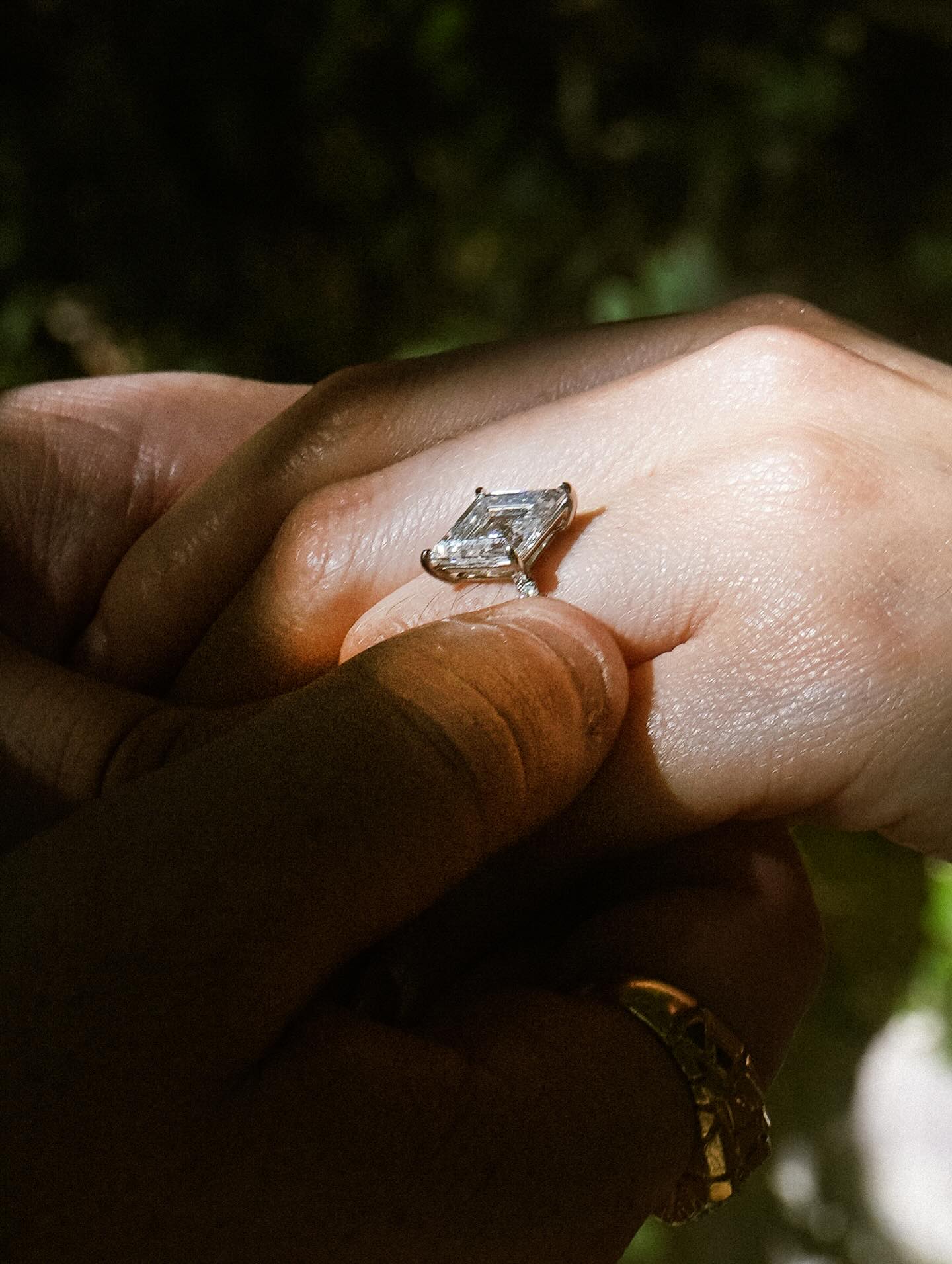 This one feels like it’s all about the celebration of love and finding your person and people in life. These two beautiful people showed up at the studio to talk about the kind of ring she had envisioned. Talking to them you could just feel how in love they were and together we figured out what would be her dream ring. As we were talking I wasn’t completely sure I could make it come together, haha, if I would be able to find this cut of stone but over the years it’s crazy how things come together for good people, the ones that make all of it a fun journey. ✨ Magically after some searching I somehow came upon a few of them and together with their close friends he decided on this beauty. ❤️ The perfect size and shape in a cut called a lozenge cut. This beauty of a stone is a geometrically shaped stone that resembles a rhombus or the diamond in a deck of cards, featuring four sometimes equal sides and pointed ends. It is a vintage, step-cut that often creates a “hall of mirrors” effect similar to an emerald cut, with elongated trapezoidal facets running down its sides and the name “lozenge” comes from the Old French word for “diamond shape.” It’s a stunning cut that makes this diamond a real true stunner. We added some tiny diamond pavé on the band and set it as low as possible in platinum so it looks like it’s floating on her finger. ✨
When he came to pick up the ring with their friends it was so beautiful to see how everyone was just so happy for their love. The proposal was no different, surrounded by all their people and these beautiful photos shot another beauty. @samsanroman Love between two people and the people you choose to live life along side is such a beautiful thing. ❤️