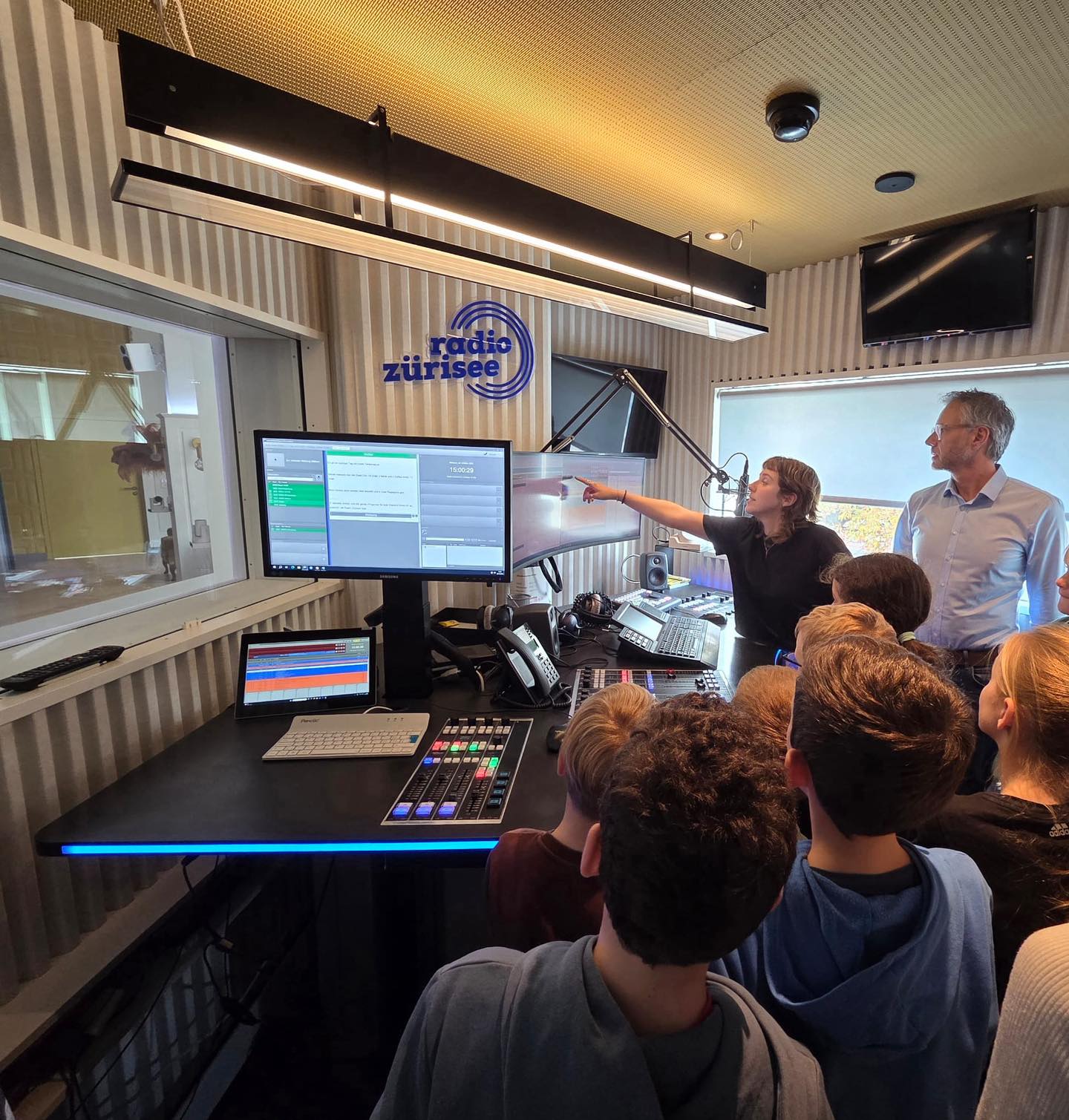 Ein Blick hinter die Kulissen von Radio Zürisee
Der Familientreff Kaltbrunn reiste für einen spannenden Mittwochnachmittagsausflug nach Rapperswil. 18 Kinder erhielten einen exklusiven Einblick in die Welt des Radios – und durften live miterleben, wie Nachrichten entstehen.
Mit grosser Begeisterung begrüsste David Nadig, stellvertretender Chefredaktor und Sportchef von Radio Zürisee, die Gruppe aus Kaltbrunn. Auf erfrischend lebendige Art führte er die Kinder durch die Studios, erklärte technische Abläufe und erzählte von den vielen Veränderungen, die das 1983 in Stäfa gegründete Regionalradio bis heute geprägt haben.Rund 30 Mitarbeitende sorgen dafür, dass das Programm abwechslungsreich und aktuell bleibt. Neben dem Radiobetrieb organisiert Radio Zürisee auch Konzerte und Events verschiedenster Grösse in Rapperswil-Jona und trägt so zur kulturellen Vielfalt in der Zürichsee-Region bei.
Die jungen Besucherinnen und Besucher erfuhren, wer beim Sender die Musikauswahl trifft, wie ein typischer Arbeitstag einer Moderatorin aussieht und welche Technik nötig ist, um überhaupt auf Sendung zu gehen. Besonders spannend war der Moment, als die Kinder eine Nachrichtenübertragung live miterleben und anschliessend das Tonstudio betreten durften.Auch die Gespräche mit den Mitarbeitenden hinter den Mikrofonen machten das Radio greifbar und hinterliessen bleibenden Eindruck. Die vielen neugierigen Fragen der Kinder zeigten, wie sehr sie sich für das Geschehen interessierten, das sonst nur über die Radioboxen zu Hause zu hören ist.
Mit leuchtenden Augen und vielen neuen Eindrücken verliess die Gruppe das Studio – und manch ein Kind träumt vielleicht nun davon, eines Tages selbst am Mikrofon zu stehen. Die Zeit verging dabei wie ein Lieblingssong im Radio: viel zu schnell, aber unvergesslich.