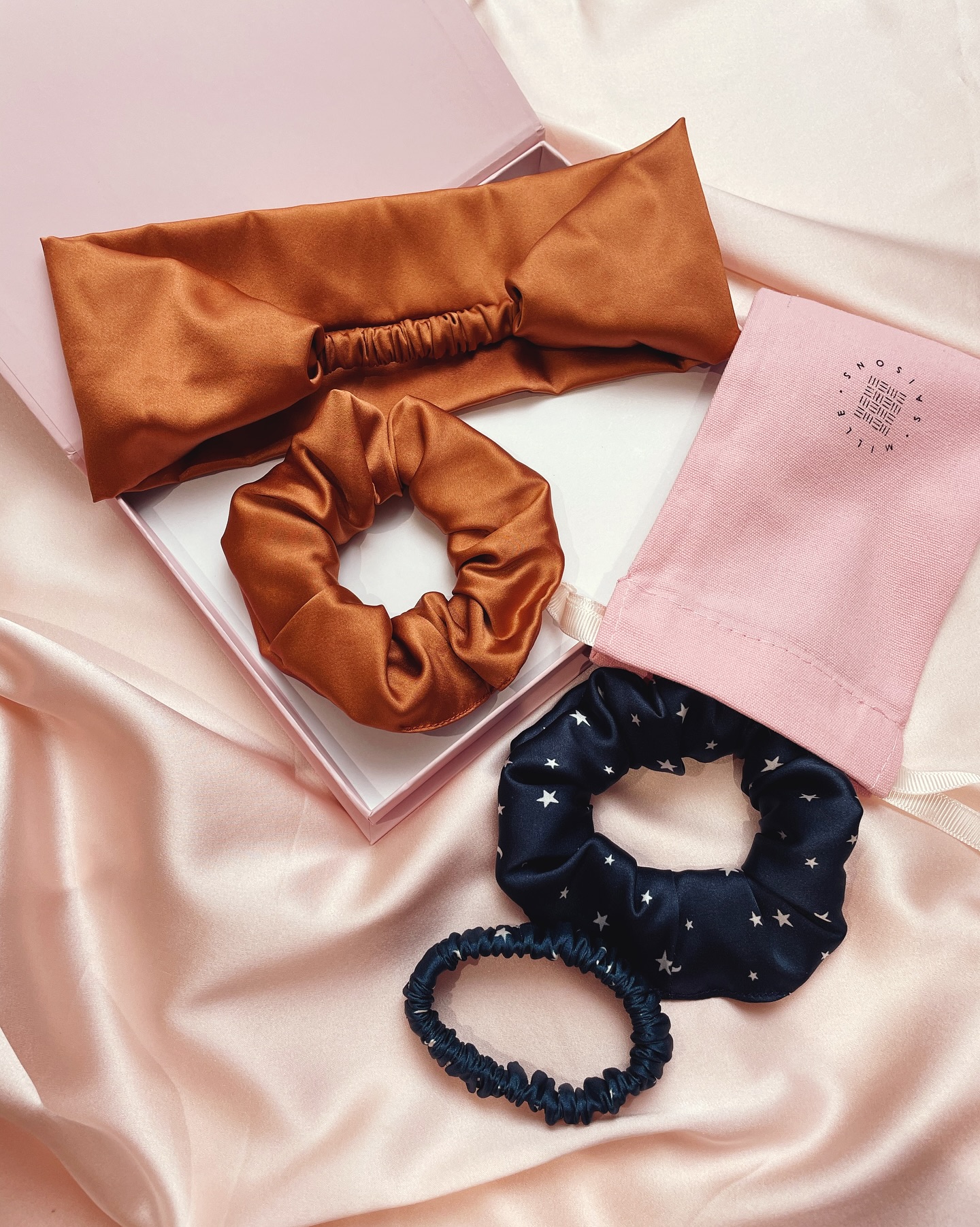 Need some ideas for late autumn birthdays (or Christmas inspo..!) then here are some silk gift sets in seasonal colours to spark some ideas. I have plenty of gift options with ready to give packaging and am always happy to put together custom options to create your ideal gift sets
Image description- 1. A copper silk scrunchie and headband in a gift box and a navy scrunchie and matching hair elastic with white star and moon print coming out of a pink Mille Saisons branded gift bag
2. A deep brown silk scrunchie and hair bow in a gift box and a red silk scrunchie and matching hair elastic coming out of a pink Mille Saisons branded gift bag
3. A red and white gingham eye mask and matching scrunchie in a gift box and three silk scrunchies in red, brown toned purple and copper coming out of a pink Mille Saisons branded mini drawstring bag