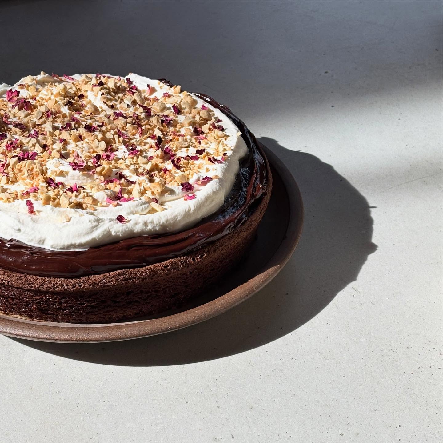 overheard that a clientâs partner is celebrating a birthday and loves chocolate cake đ this is an olive oil chocolate cake with sour cream ganache and rose water whipped cream, topped with toasted cashews and rose petals ofcđĽ