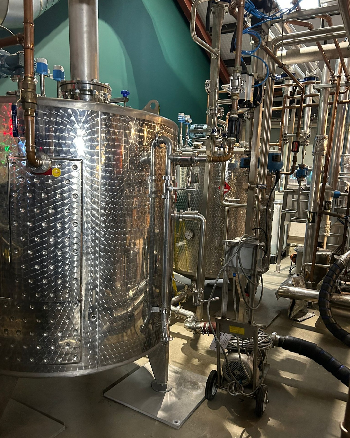 Gin botanical maceration and energy recovery pre-heating system installed at Sipsmith in order to double distillation capacity.
By diverting the hot water coming from the stills condenser to a jacketed vessel storing spirit, energy can be recovered for warming the next distillation charge to reduce cycle time and overheads.
Along with the addtional safety features required to store heated alcohol, pipework design is critical to prevent back pressure and guarentee that condenser performance isn’t affected whilst also ensuring that the vessel's jacket is functioning optimally.
This method of energy recovery can be employed in tandem with closed-loop refrigeration helping to decrease the work required by the chiller and reduce water consumption as well as energy.