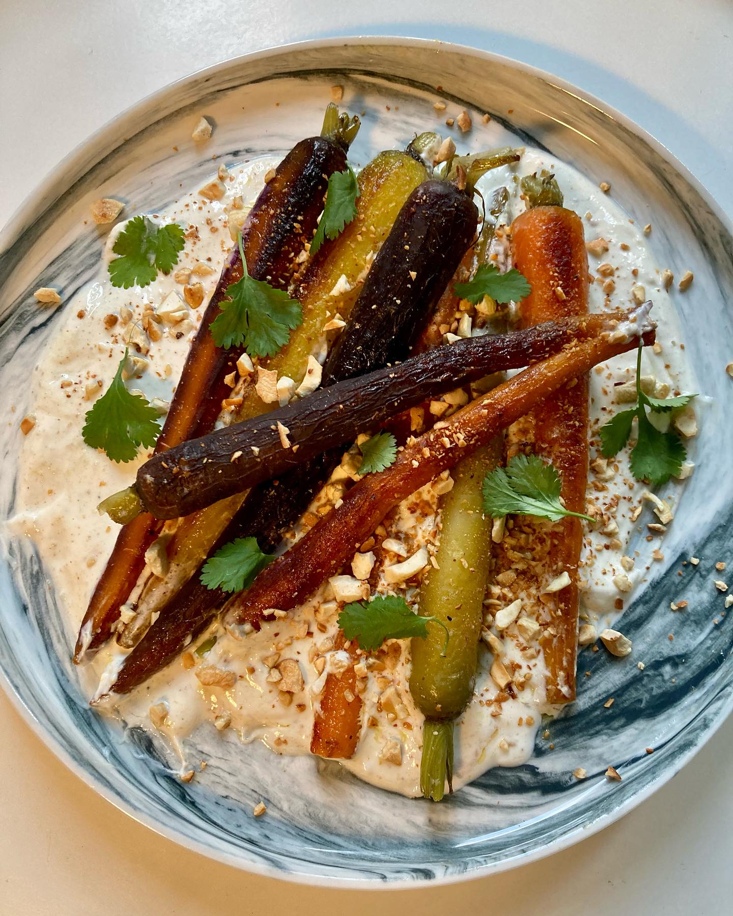 Carottes rôties, sauce yaourt, noix de cajou, cumin!
Il me fallait une belle recette pour sublimer ces magnifiques carottes nouvelles multicolores et aussi pour ne pas jeter les fanes tant qu’à faire…
Du coup, deux recettes à vous proposer, celle-ci et une soupe aux carottes et fanes que je vous donnerai bientôt!
J’ai fait un 1er essai de cuire les carottes rôties au four, elles dessèchent et perdent de leur magnifique couleur.
Le mieux est de les cuire à la vapeur 20 minutes et de les faire revenir à la poêle avec du beurre, pour qu’elles puissent bien briller (je n’ai toutefois pas fait comme les grands chefs, d’y mettre toute la tablette!). Et pour un côté très gourmand, j’ai préparé une sauce au yaourt grec qui ajoute la touche orientale et un peu d’acidité, pour équilibrer avec la douceur de la carotte!
.
Pour 2 personnes: 10 petites carottes nouvelles (si possibles multicolores), 30g de beurre, 2 yaourts grecs de brebis, 1 c.à soupe de purée de noix de cajou, 1 c.a café de cumin, 1/2 c.a café d’ail en poudre, le jus et zeste d’1/2 citron bio, 1 c.à soupe d’huile d’olive, sel, poivre.
Couper les tiges, éplucher si nécessaire (si elles ne sont pas bio) les carottes, les passer sous l’eau. Les mettre dans un panier vapeur et les cuire 20mn à partir de l’ébullition.
Mettre le beurre dans une poêle, faire revenir à feu vif les carottes en les retournant, régulièrement, jusqu’à ce qu’elles soient dorées, soit environ 15mn.
Écraser les noix de cajou et les faire dorer à sec dans une poêle.
Mélanger de façon homogène le yaourt avec le reste des ingrédients. Saler, poivrer, réajuster l’assaisonnement selon son goût.
Dans chaque assiette, repartir le yaourt sur le fond, les carottes sur le dessus, saupoudrer de noix de cajou grillées et de quelques feuilles de coriandre (facultatif). Arroser avec un filet d’huile d’olive.
Bon appétit!
.
#carottes #carotte #carottesmulticolores #yaourt #noixdecajou #alaottolenghi #cumin #zestedecitron #dietetiquechinoise #madreperlamtc