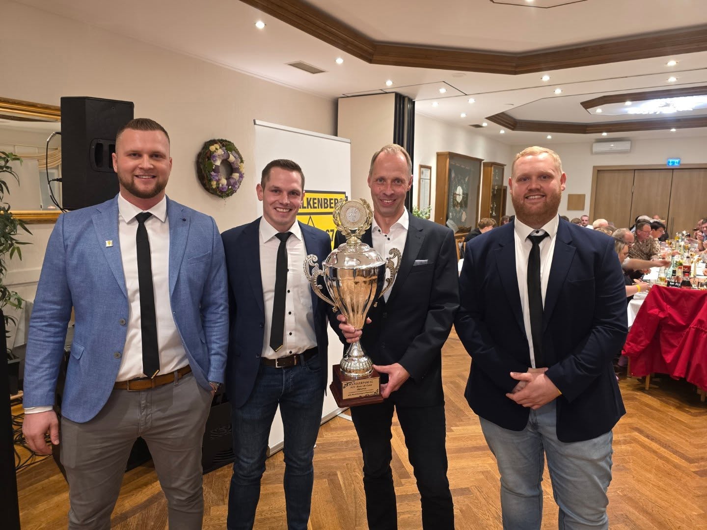 + Jeden Tag eine Ehrung + *
Altherren*
Patrick Säger (1. Vorsitzender), Klaus Buschermöhle (Altherrenobmann), Jürgen Hülskamp (Spieler Altherren), Lukas Brandewie (2. Vorsitzender)
Unsere Alt-Herren haben dieses Jahr wieder an der „Oldenburger Runde“ teilgenommen – einer selbstorganisierten Liga freiwilliger Alt-Herren-Teams. Mit starken Leistungen in acht Spielen, insgesamt 20 Punkten und einer Tordifferenz von +20 sicherten sie sich mit sechs Punkten Vorsprung souverän den ersten Platz. Heute dürfen wir deshalb eine besondere Pokalübergabe feiern.