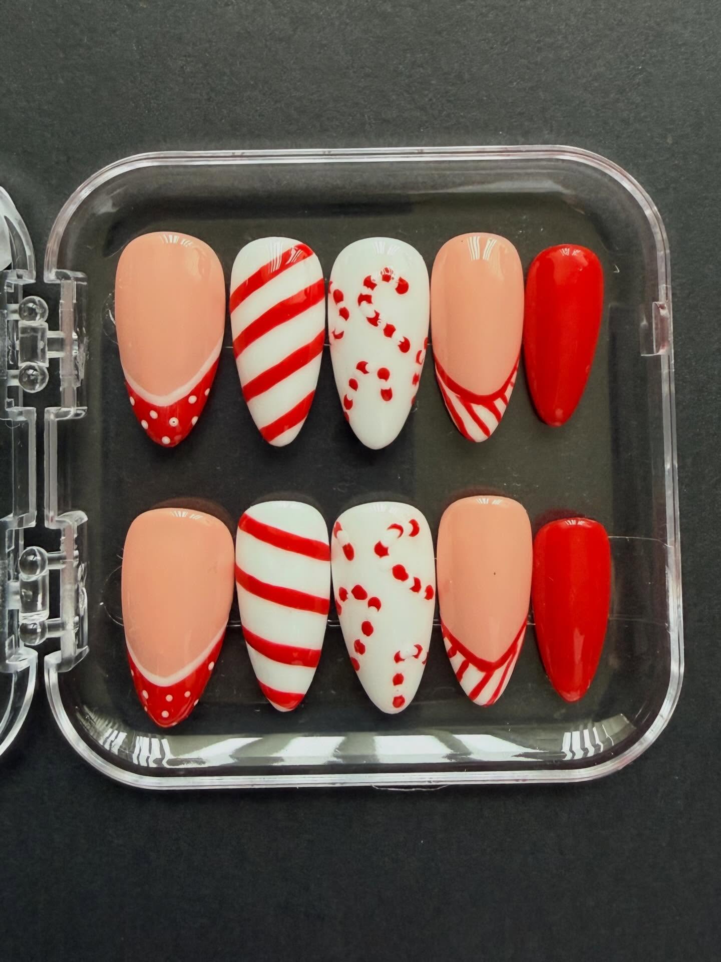 Hand painted red and white Christmas candy cane press on nails with candy cane nail art and french tips #nailsnailsnails #christmasnails #nailart #christmas #naildesign #handpaintednails #nailartist #candycane