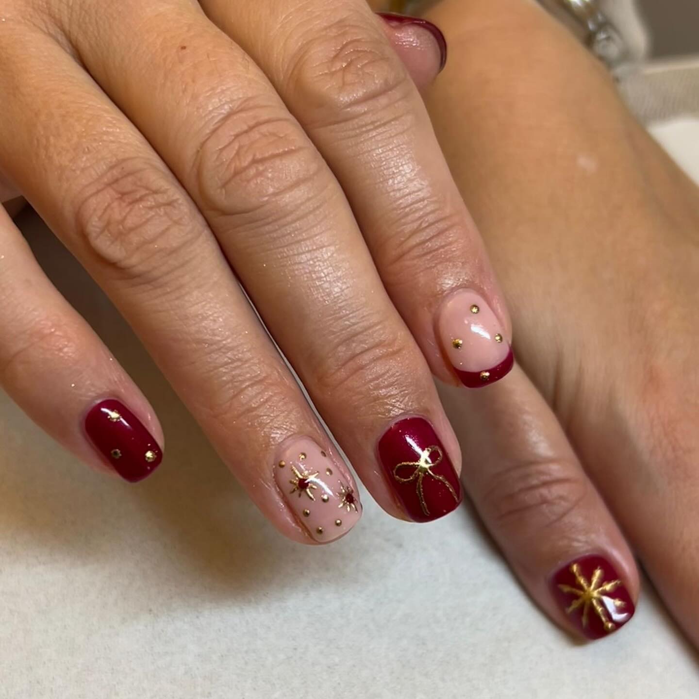 Festive Christmas nails using Carmilla from CALGEL with golden accents ✨ Gift-wrap ribbons, tiny studs, and soft nude details make this set elegant, cozy, and perfect for a holly jolly Christmas 🎄 ✨🎀