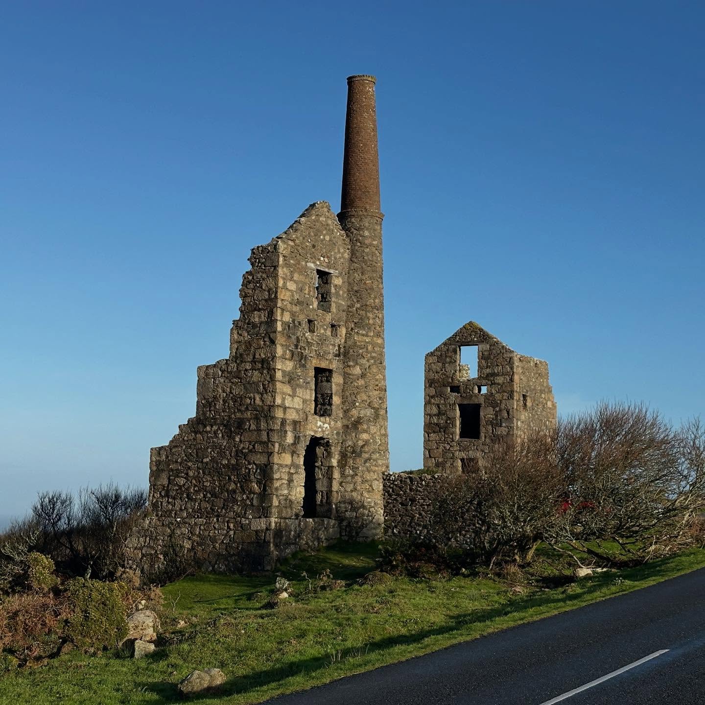 Had a fab Geowalk to Bosigran and Carn Galver, blessed with a brief window of late autumn sunshine!
Carn Galver engine houses were looking resplendent in the morning sun.
Carn Galver Mine was worked during the 19th Century, either independently or as part of Morvah and Zennor United Mines.
Production was intermittent, and limited output records 150 tonnes of black tin extracted in the second half of the 19th Century.
The two engine houses at the side of the road were built during the last attempt at working the mine in 1871.
The left hand structure housed a 30” pumping engine, and structure to the right just behind contained a 22” winding engine. The shaft used by the pumping engine reached a depth of 240 m.
The building just out of shot to the north of the engine houses was the mine’s count house, now used by the Climbers’ Club.
Rivers running down adjacent valleys to Porthmoina Cove and the neighbouring Porthmeor Cove were utilised for their water power to process the mined rock – to crush it down and separate out the heavy tin ore from the gangue (waste) minerals.
#carngalver #bosigran #carngalvermine #tincoast #geologyfieldtrip #granite #landsendgranite #enginehouse #cornishmining #ordnancesurvey #cornwall #cornwallcoast #cornishcoast #walkingcornwall #explorecornwall #lovecornwall #cornwallgeology #cornishgeology #geology #geologyrocks #geolife #geologist #geologistsofinstagram #learninggeology #geoadventure #exploregeology #geologicalwonders #penwith #swcoastpath #geologylife