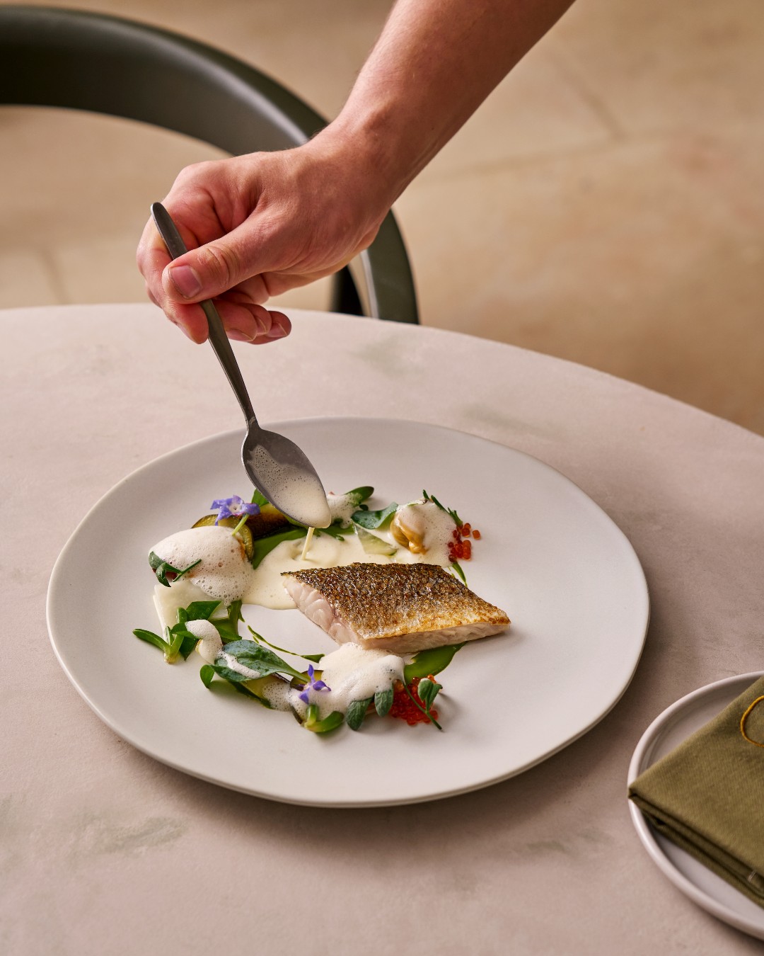 Our Wild Line-Caught Cornish Seabass from @flyingfish525 with tender courgettes, sea herbs and a roasted fish bone sauce - a dish that perfectly balances fresh and light flavours with a savory, umami finish.