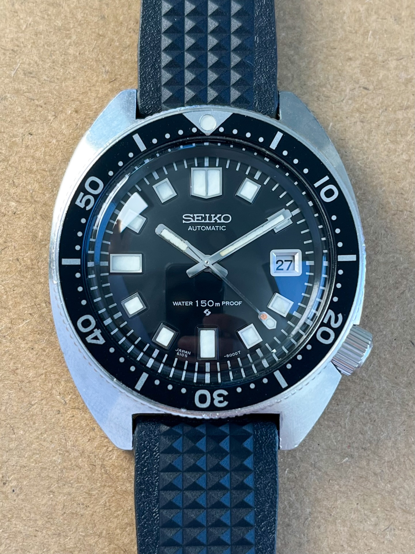Available! A superb and entirely original Seiko 6105 “Slim Case” diver from April 1968, one of the earliest executions of Seiko’s most iconic military-era tool watch. The 6105 earned its reputation in the field during the Vietnam War, where U.S. servicemen relied on it for its uncompromising build quality, reliability, and ability to survive extreme heat, humidity, and constant exposure to the elements. Early examples like this one, preserved in honest and exceptional condition, have become increasingly difficult to source.
Just serviced, including all new seals to the case back, crystal, and crown this example is running beautifully and remains in remarkable condition with only light, honest signs of wear. It also comes with an original Seiko 6105 presentation box, a rare and highly collectible addition seldom seen with these watches.
Collectors will immediately appreciate the presence of every factory original component, including the sought-after horseshoe case back, original bezel and long sweep seconds hand, details that define the earliest production 6105 models. A new Uncle Straps 19mm waffle strap has been fitted for period correct look.
The case retains its untouched factory finish, free from any re-polishing and with a beautiful sharp edge. The dial and hands feature entirely original lume that has aged gracefully and remains in excellent condition, something that continues to set the true survivors apart from restored or relumed examples. A new crystal has been installed for clarity, with the original crystal included for provenance. The quick-set date operates flawlessly, as stated the watch has just undergone a full service, with fresh seals. Head over to our website for more details and to purchase! #vintageseiko #seiko6105 #watchforsale