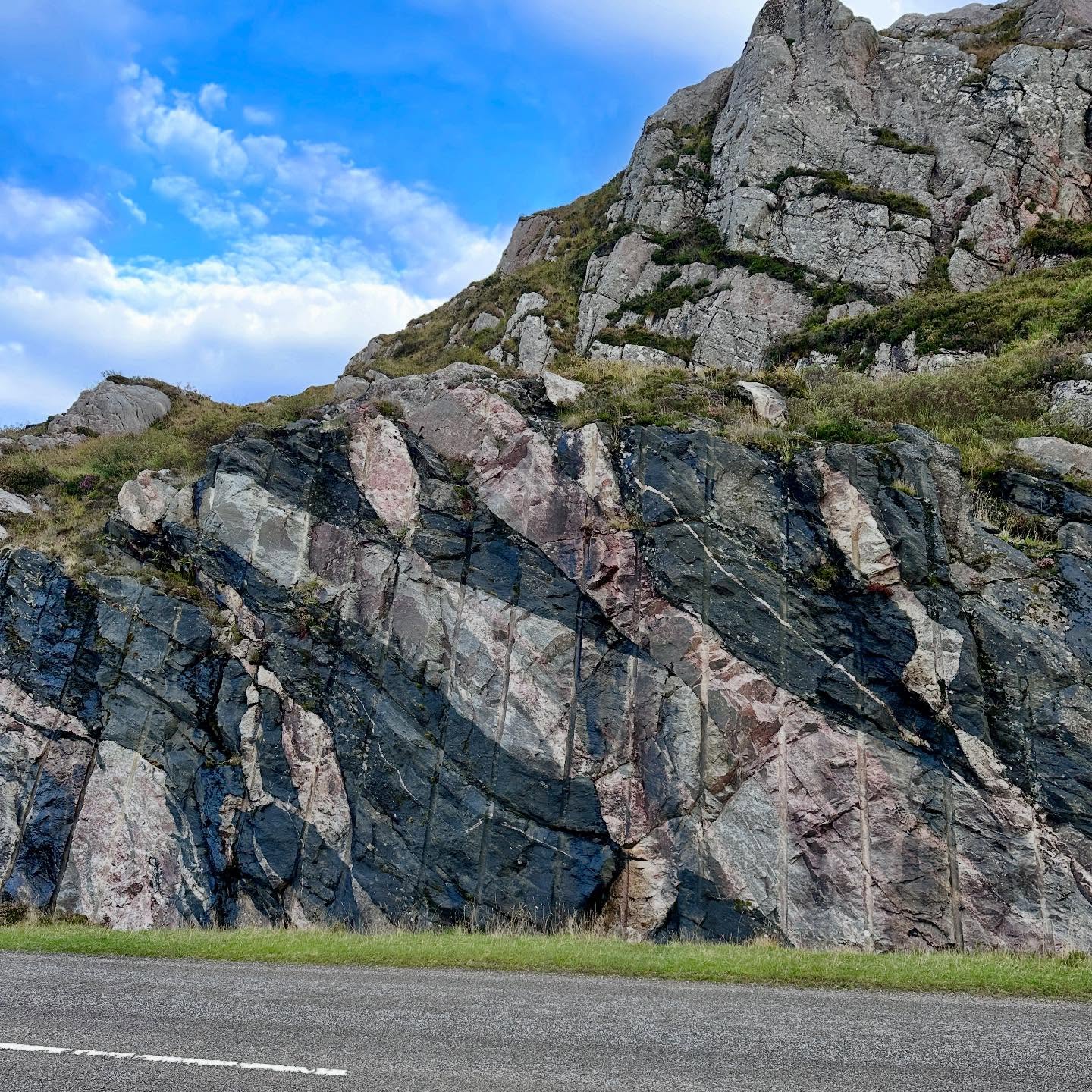 Reminiscing about our amazing trip to Scotland last year, especially visiting this place.
This is the incredible exposure of the Lewisian Complex in a road cutting just north of Laxford Bridge - some of the oldest rocks in Britain.
This road cutting beautifully displays the long and complex history of the Lewisian. Detail can be missed where it has a dull weathered crust, so these fresh exposures are a geologist’s dream!
The Lewisian Complex is part of the North Atlantic Craton and consists of high-grade metamorphic basement rocks. It crops out across the Outer Hebrides and the NW of Scotland.
It is also called the Lewisian Gneiss (pronounced “nice”). Gneiss is a coarse-grained, banded metamorphic rock. They form deep in the Earth’s crust, experiencing immense temperatures and pressures that can eventually cause partial melting.
Rocks that make up the Lewisian represent several geological events. They formed during the Archean and Paleoproterozoic; that’s between 1.7 and 3 billion years ago!
It includes felsic igneous rocks, e.g. granite, that formed 3 billion years ago, undergoing granulite-facies metamorphism during the Scourian Event around 2.5 billion years ago.
These rocks are crosscut by black basaltic intrusions known as the Scourie Dyke Swarm. They are seen across the Lewisian Complex, forming around 2.4 billion years ago.
Another deformation and metamorphism event occurred 1.7 billion years ago, where partial melting produced a final intrusive event where coarse pink granite sheets cross-cutting all previous rocks.
The Lewisian was eventually exhumed around a billion years ago. At the surface it began to weather and its sediment washed down rivers to form the Torridonian Sandstone.
#geopark #lewisiangneiss #gneiss #metamorphic #laxfordbridge #scotland #scottishhighlands #scottishgeology #walkingscotland #lovescotland #explorescotland #geology #geologyrocks #geolife #geologist #geologistsofinstagram #learninggeology #geoadventure #exploregeology #geologicalwonders #geologylife #geologyfieldtrip #amazingscotland #geoscience #earthscience #nc500 #northcoast500 #metamorphicrock #igneous #geologywonders